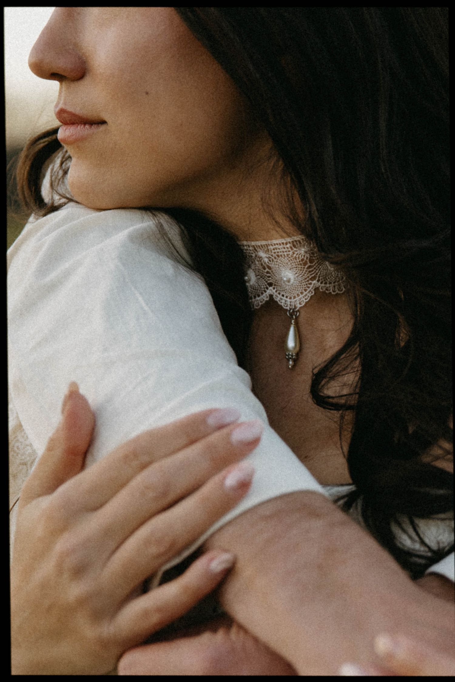 Close-up shots of delicate pearl and silver jewelry being worn with a white garment.