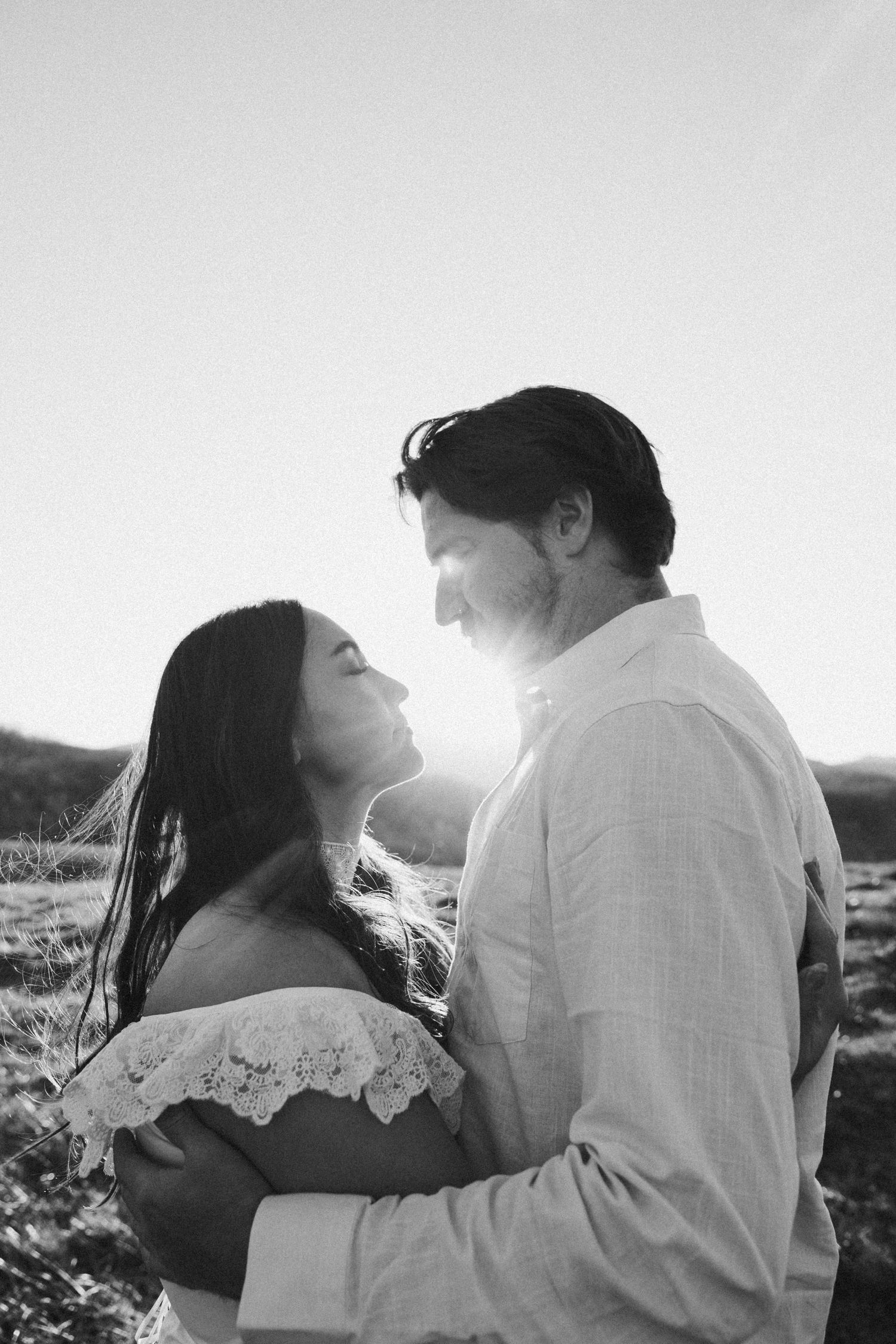 A romantic black and white photo series showing a couple embracing in sunlit outdoor moments.
