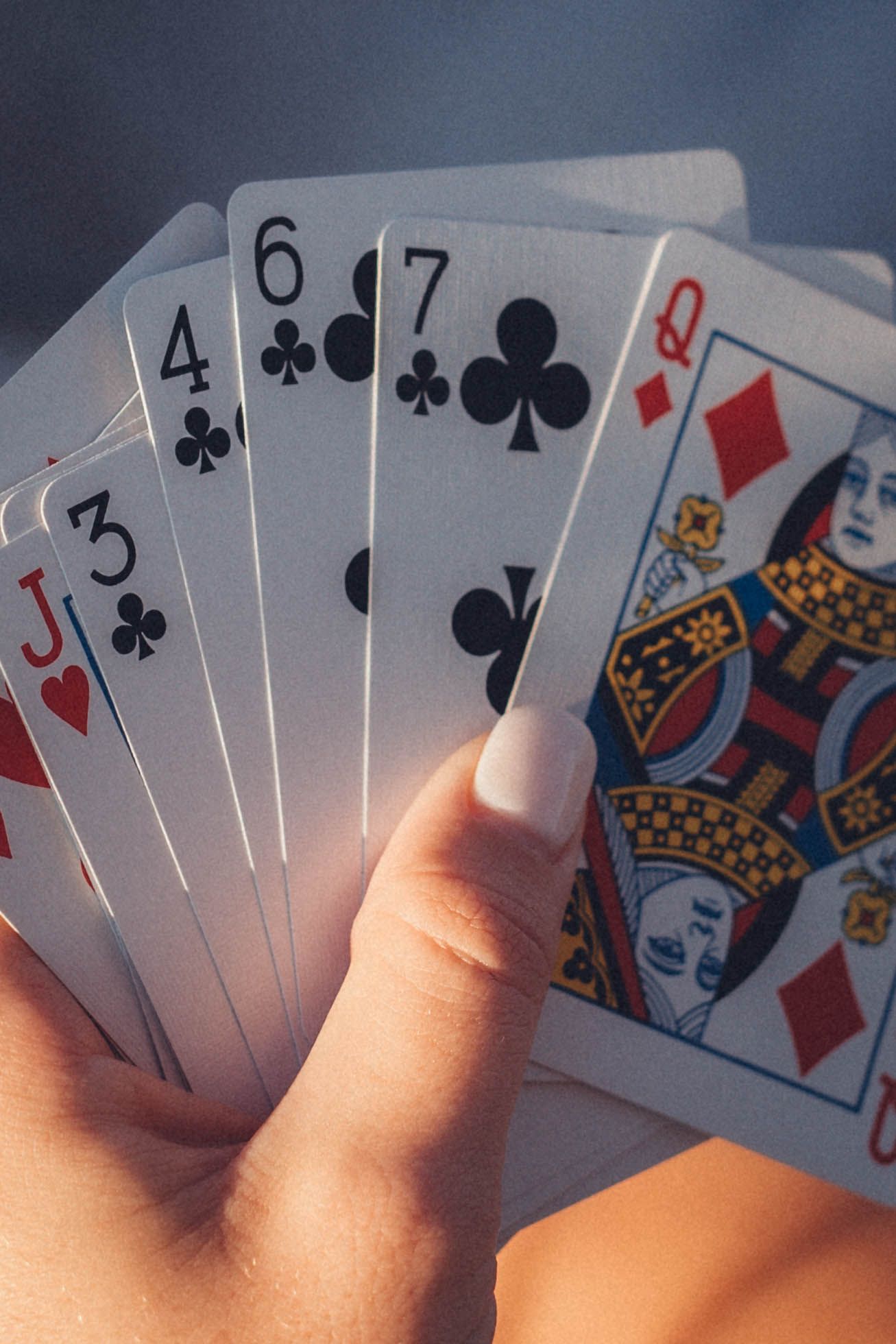 Playing cards held in hand showing a poker straight with face cards.