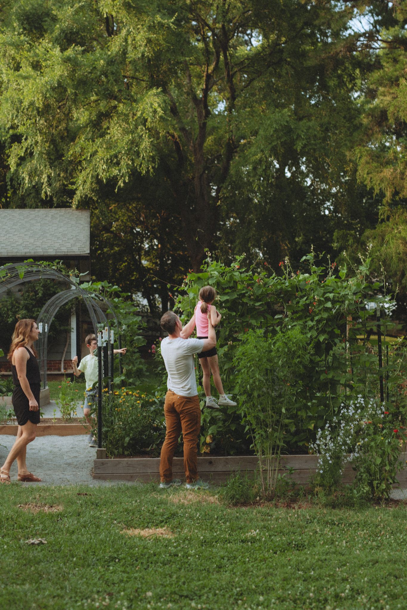 Multiple people photographing flowers in a garden with raised planter beds.