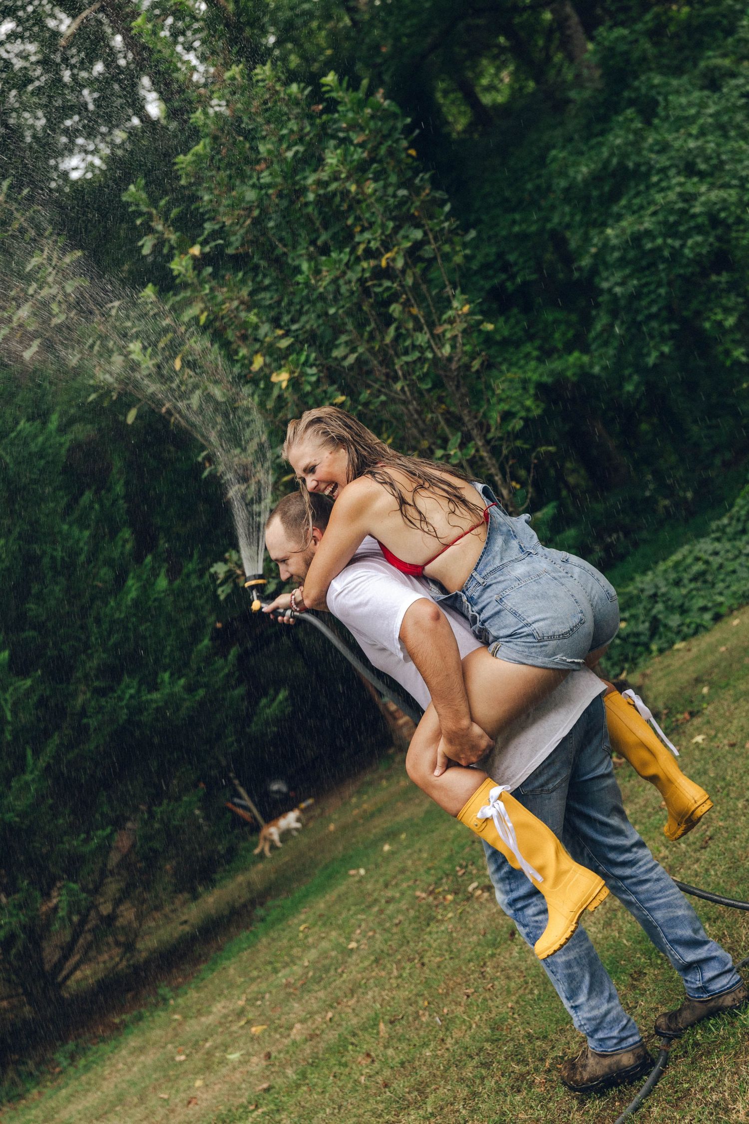 Playful photoshoot in yellow rain boots on grassy hillside.