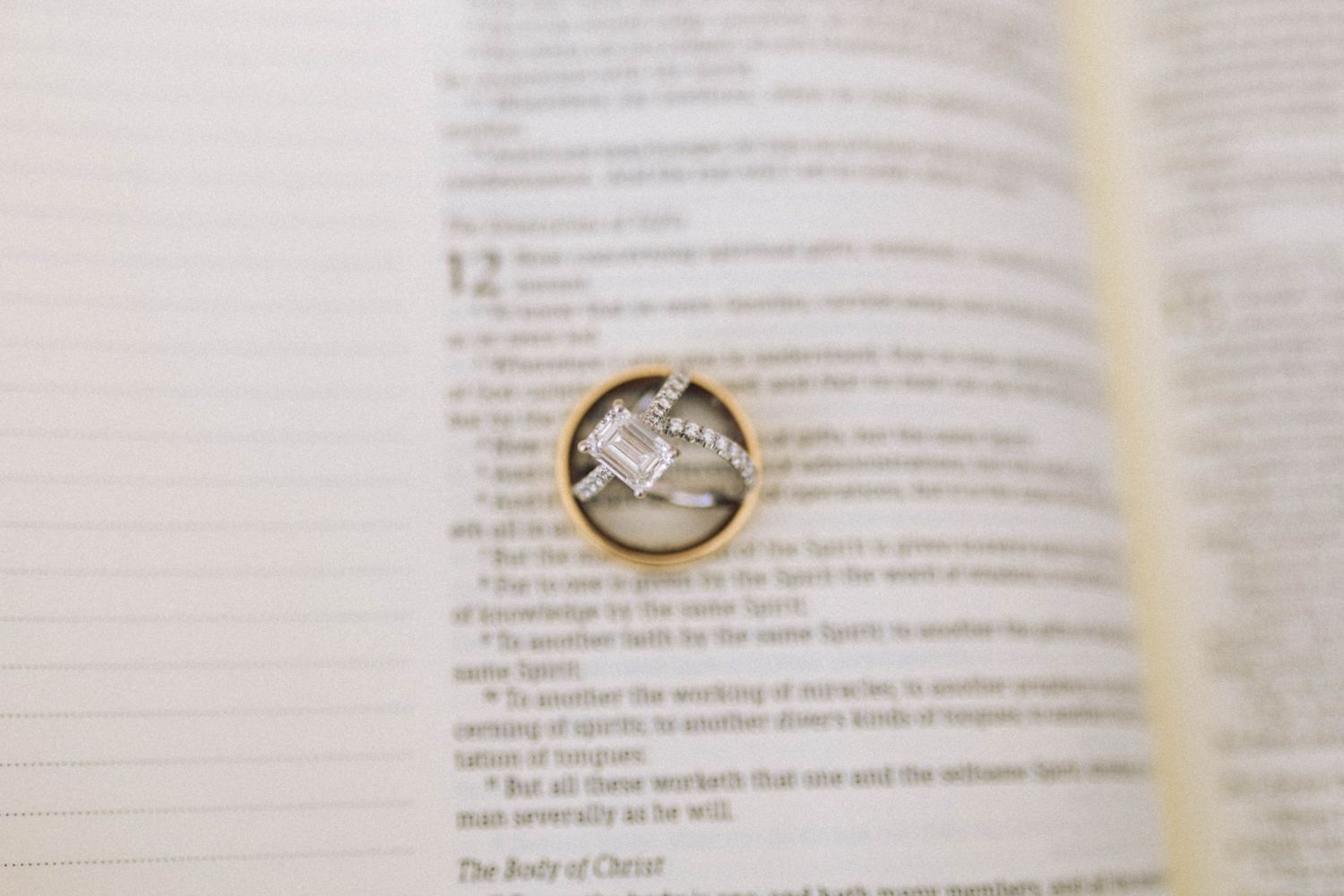 Wedding rings photographed on open book pages with shallow depth of field.