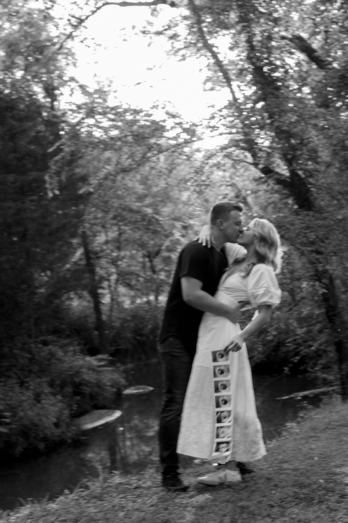 A romantic black and white portrait captured in a wooded setting.