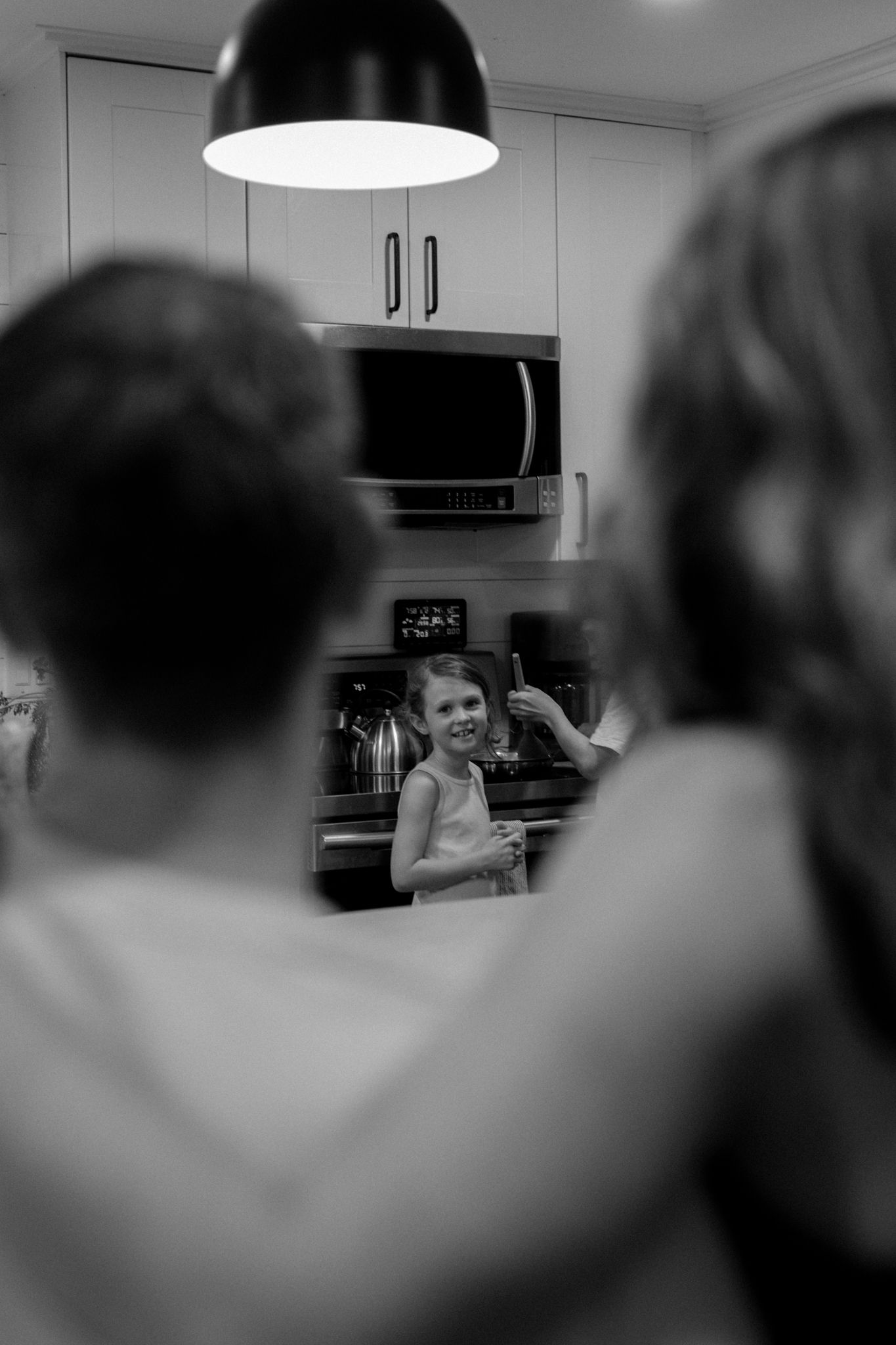 Black and white interior kitchen scene with blurred figures in foreground.
