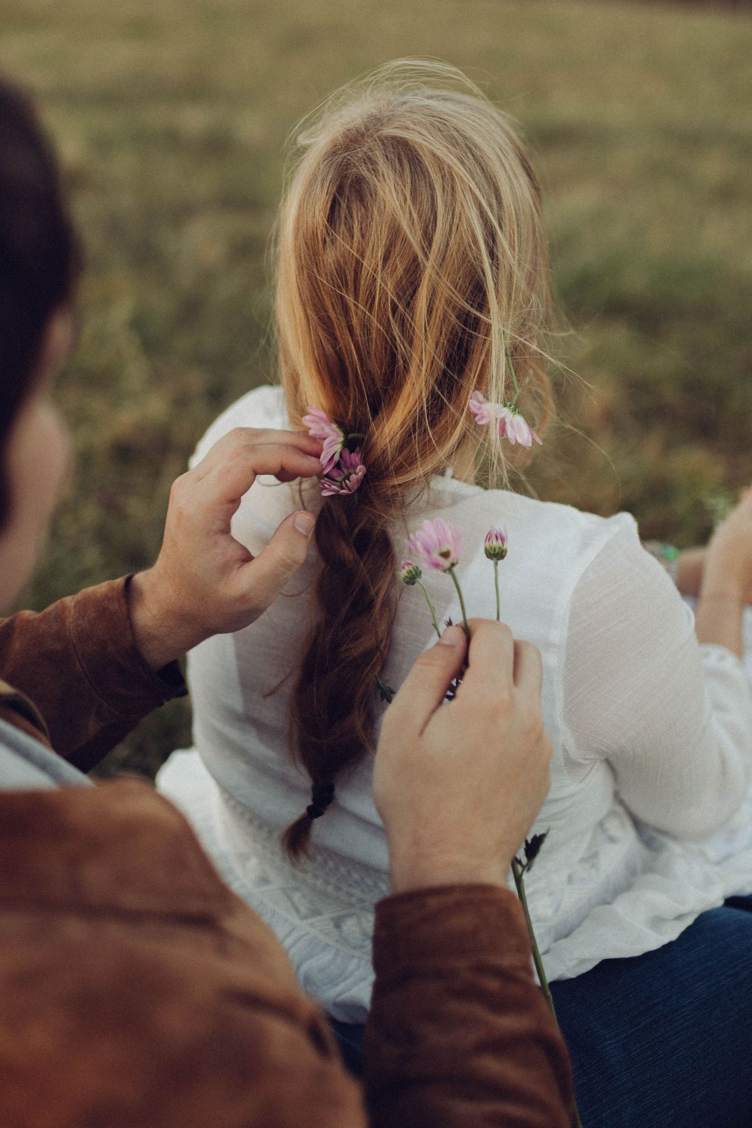 Two lovers share a tender moment on a grassy hillside during magic hour.