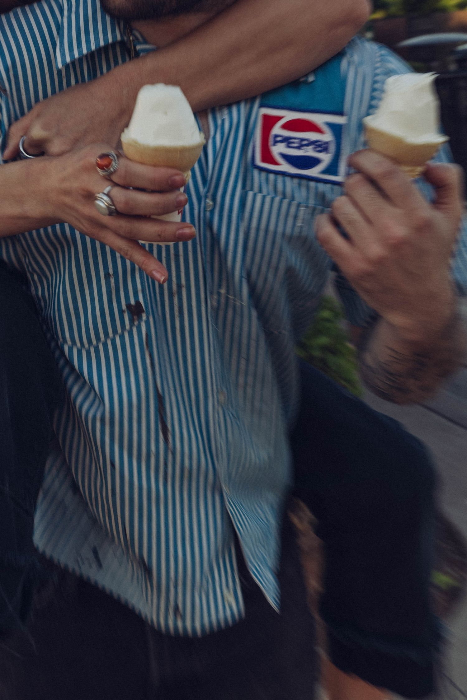 Several hands in a casual setting holding beverages and socializing against a striped background at a gathering.