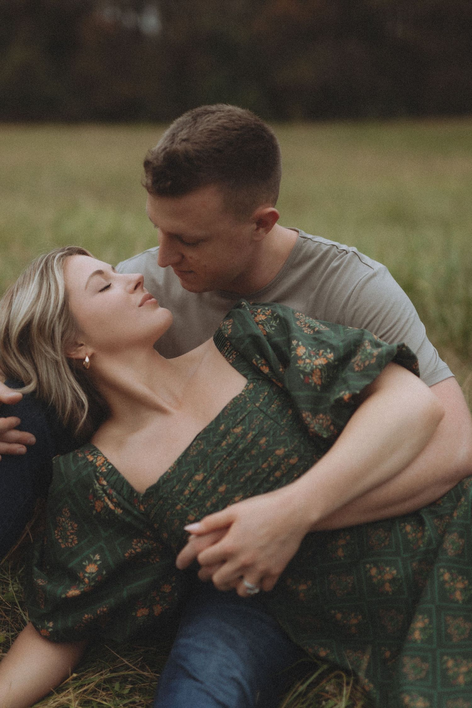 Romantic couple shares intimate moments while lying in green grass outdoors.