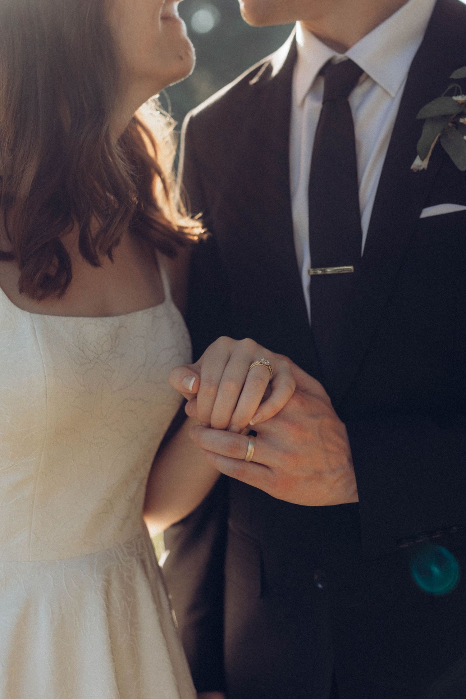 Close-up shots of hands showing wedding rings and gentle embraces during a wedding celebration.