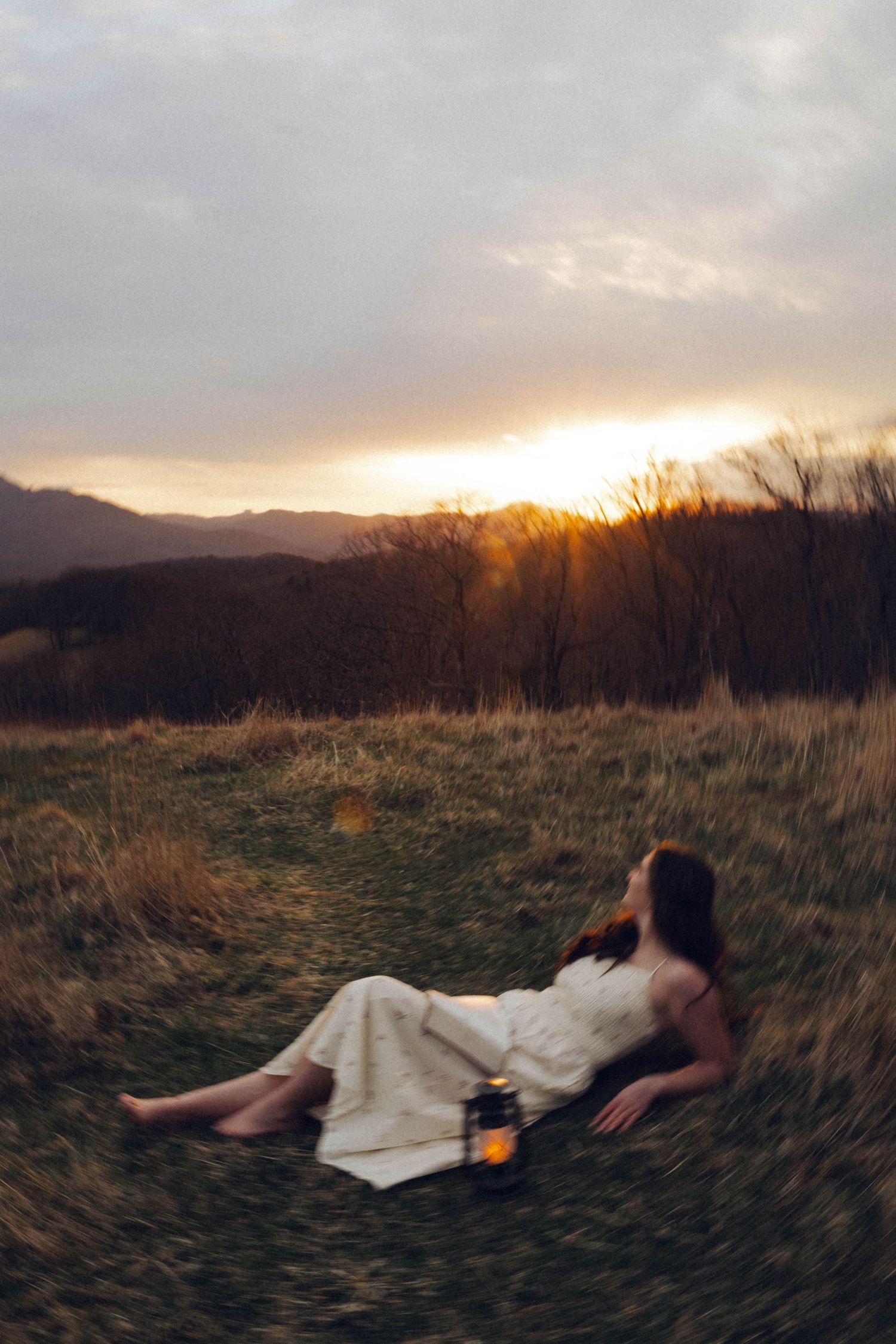 Dramatic sunset over mountain landscape with golden light illuminating field.