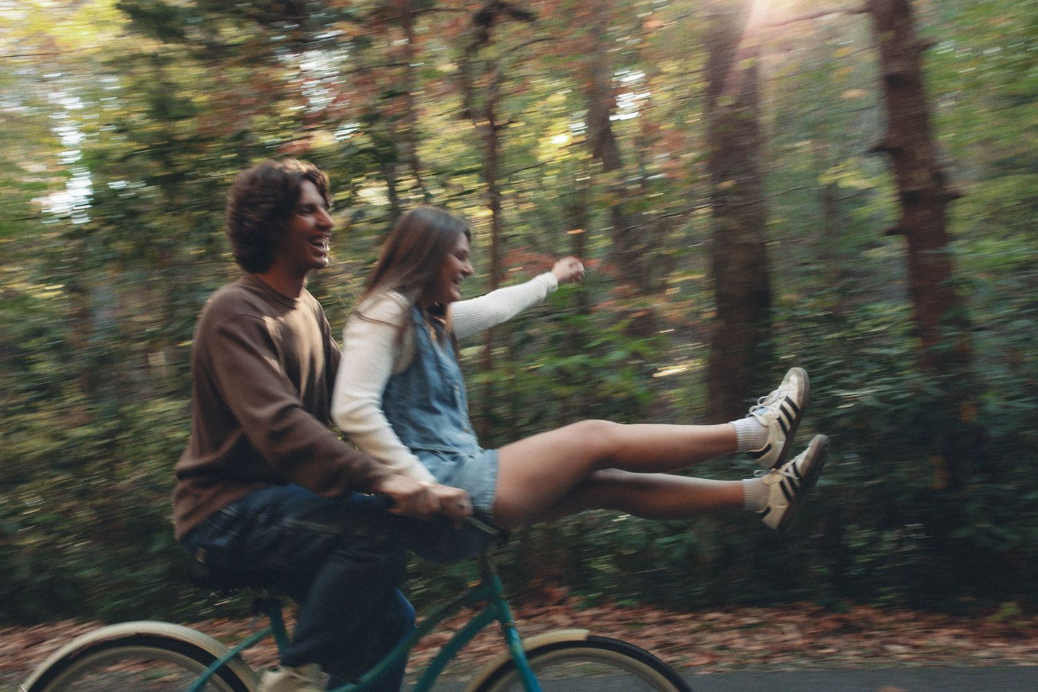Couple playfully runs through a wooded forest path together.