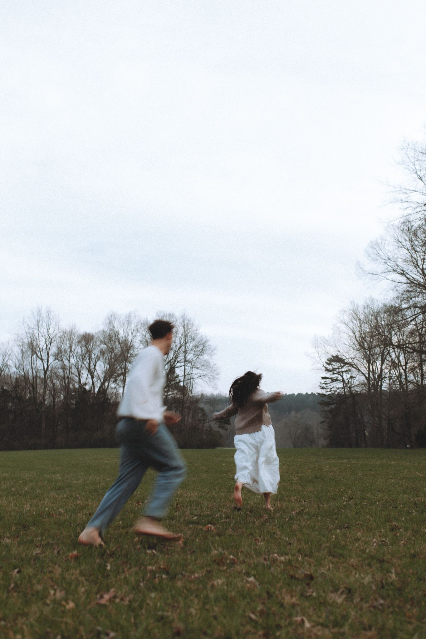 Playful sequence of two people running and jumping in a grassy field.