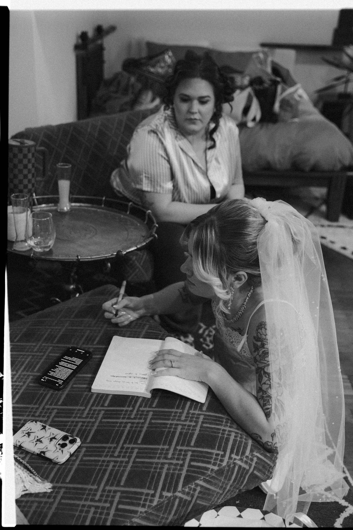 A sequence of black and white photos showing someone writing or drawing at a table with a patterned tablecloth.