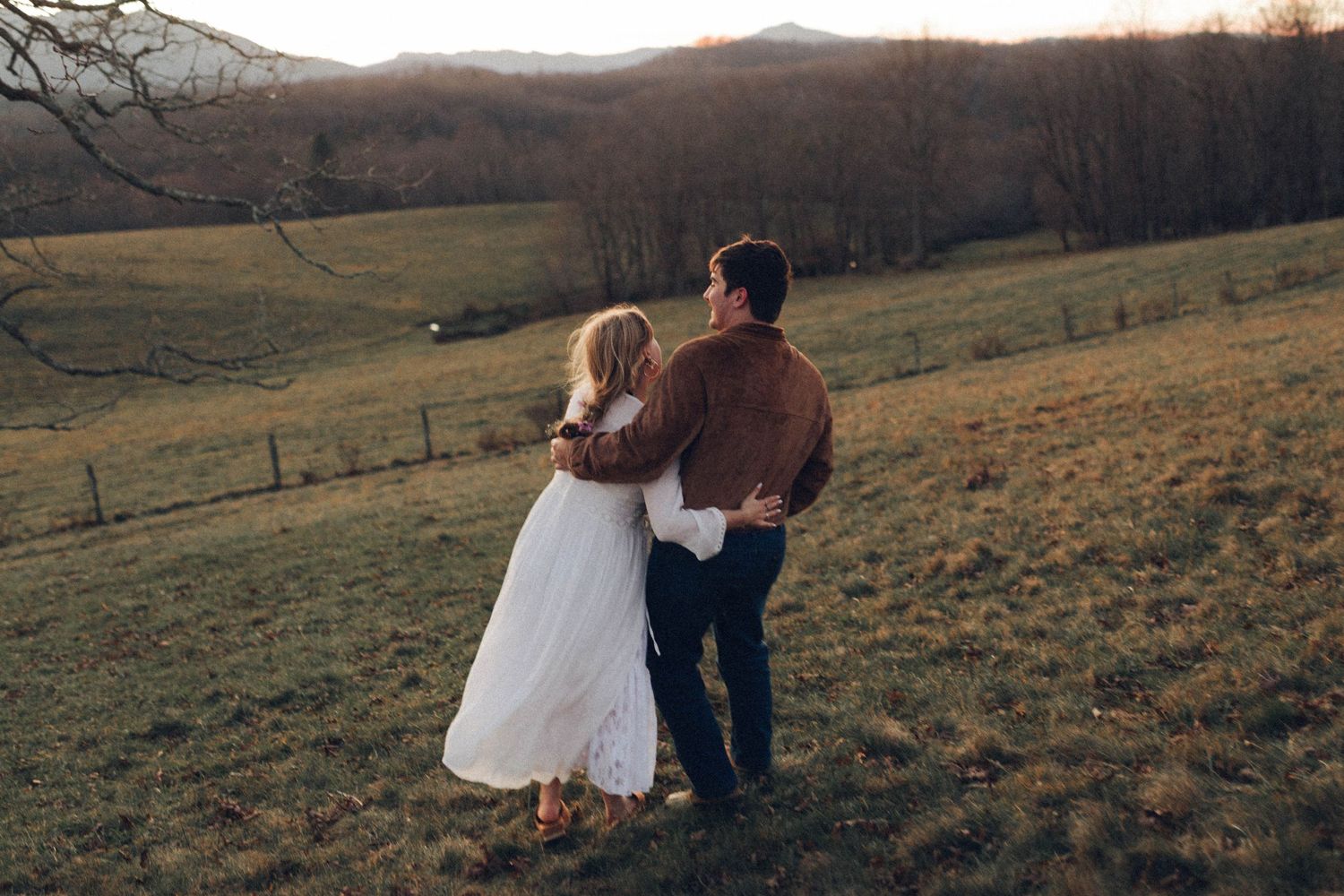Rolling hills and mountains create a dramatic landscape at sunset.