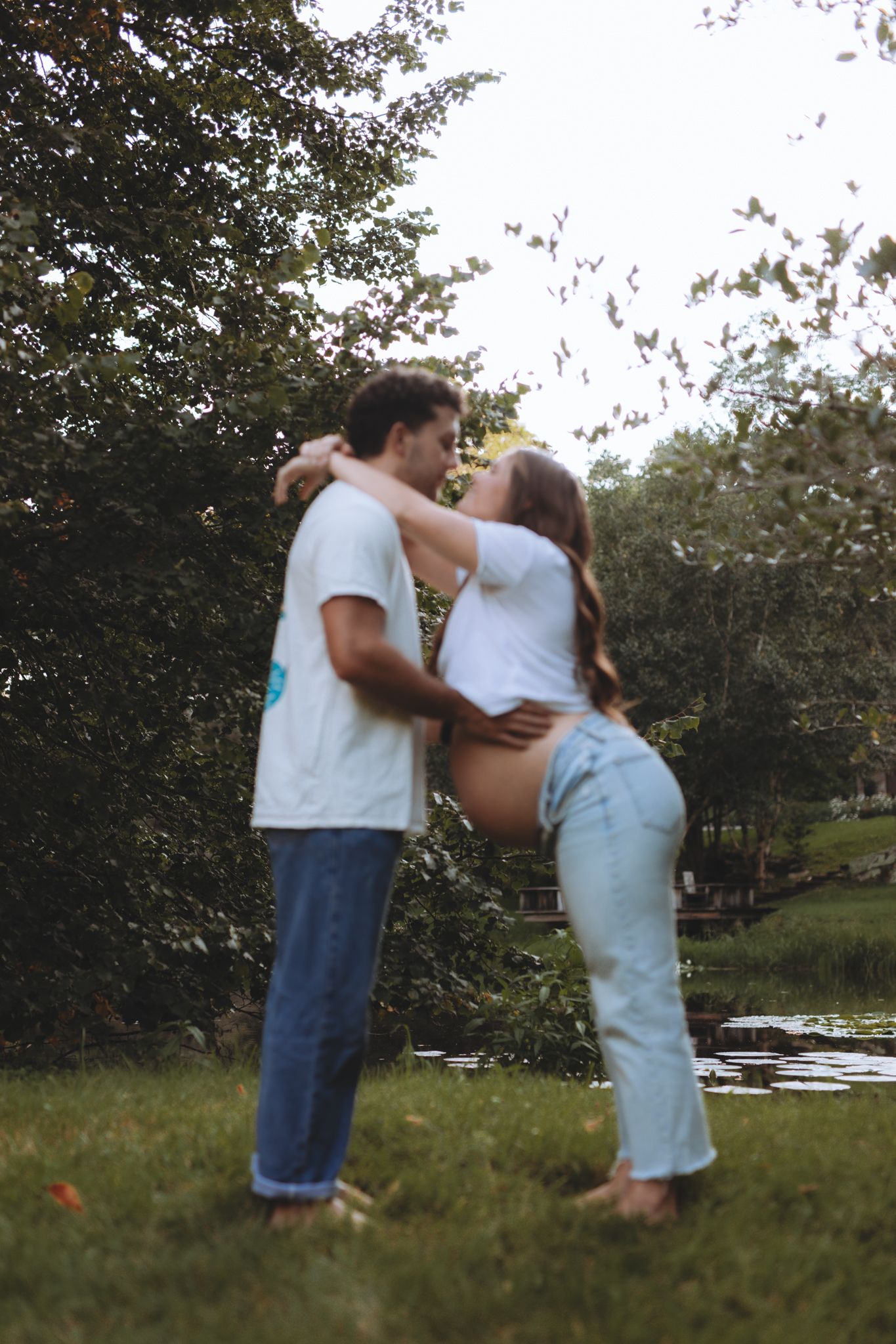 Couple embracing on grassy hillside during outdoor photoshoot.
