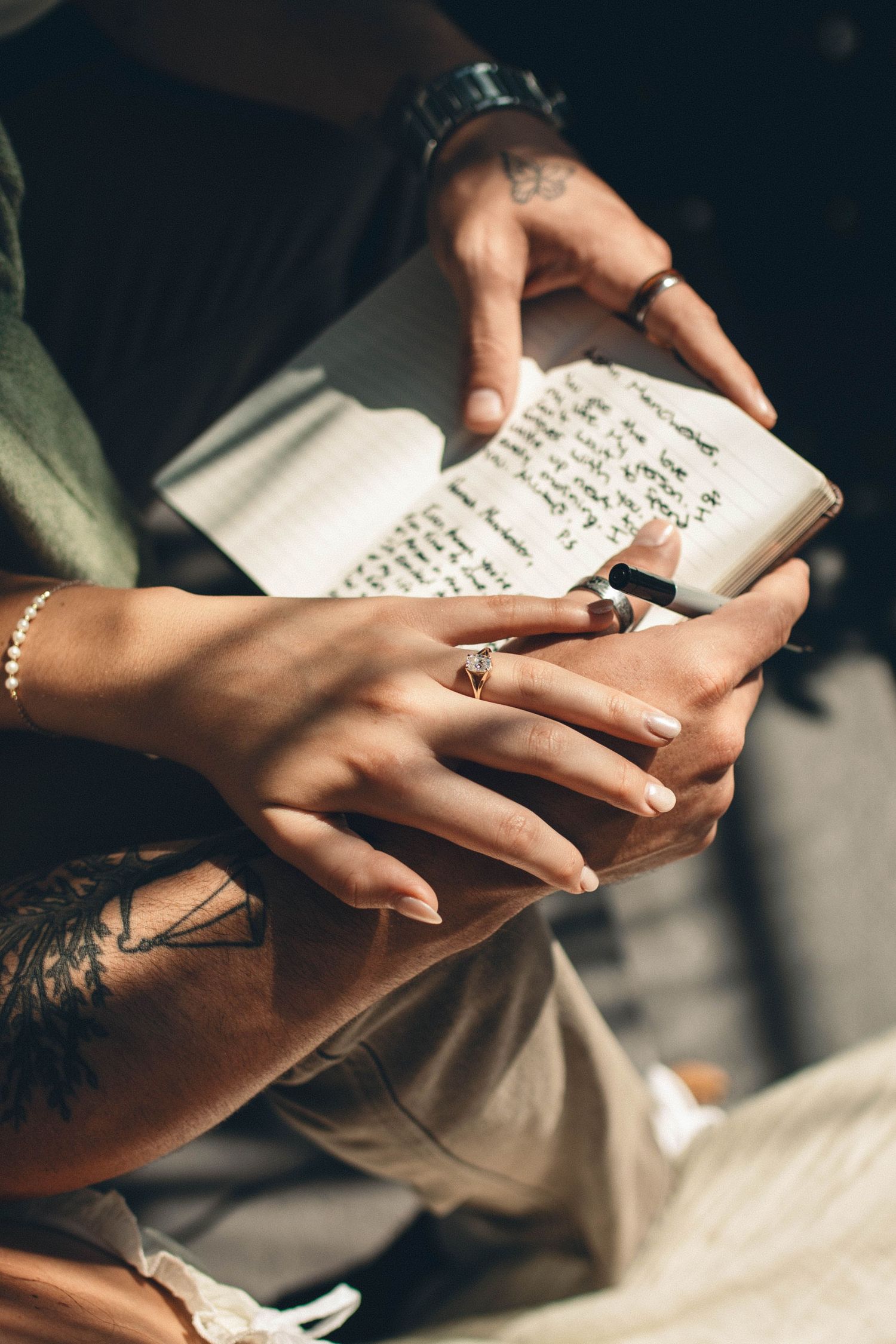 Hands delicately holding and writing in an open journal with handwritten text.
