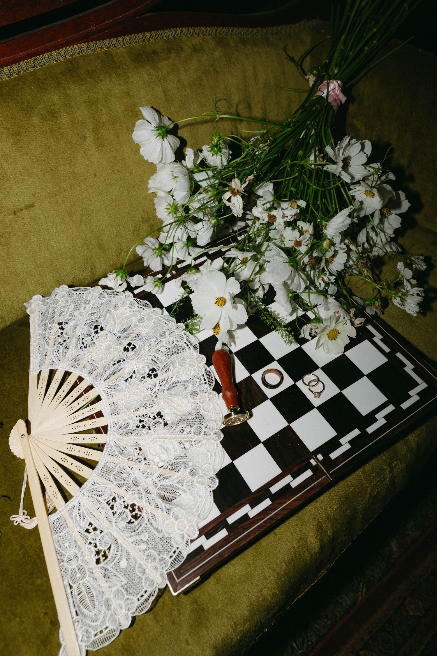 A white lace hand fan rests on a black and white checkered surface in a sequence of progressive opening positions.