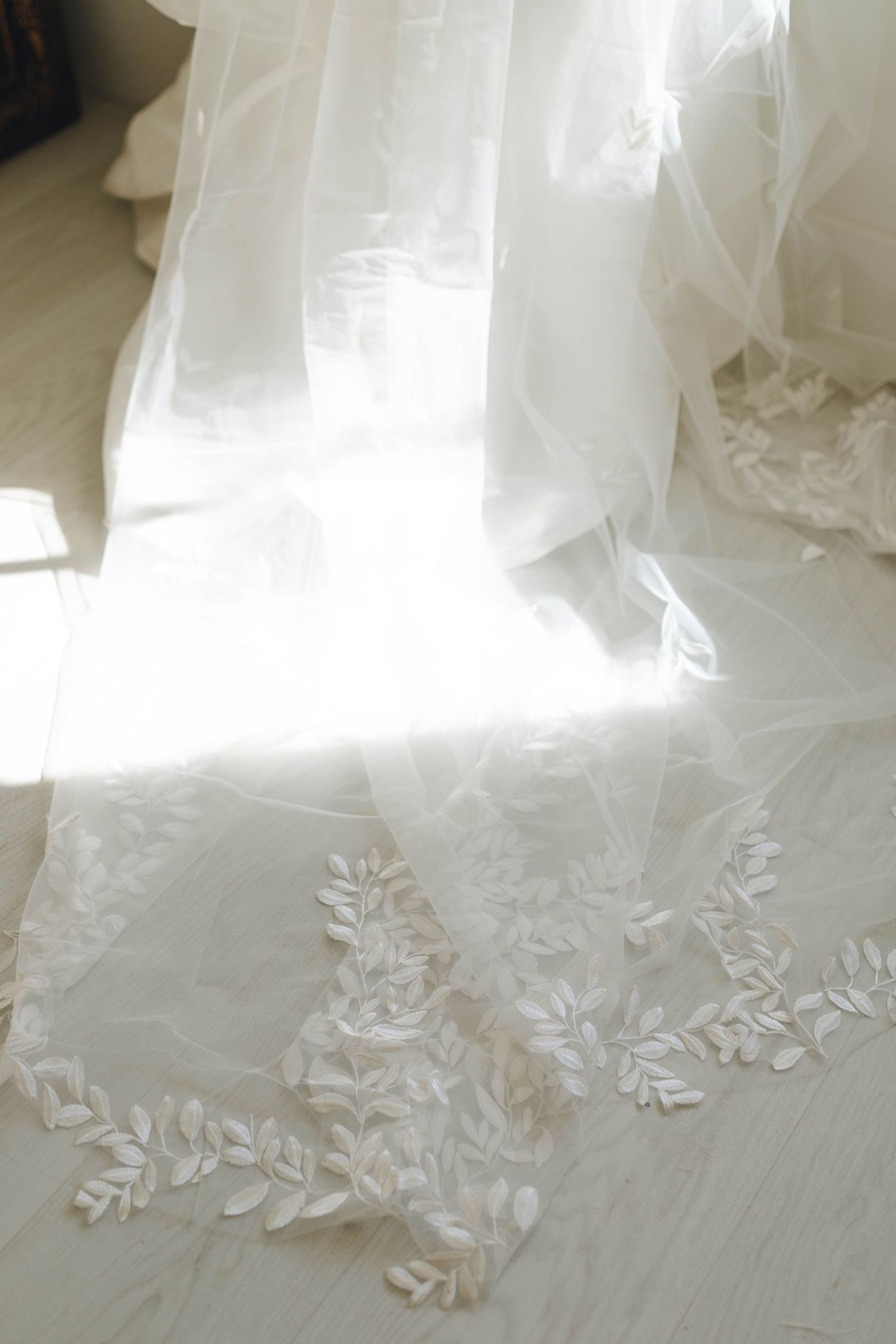 Delicate lace details on the hem of a flowing white wedding dress.