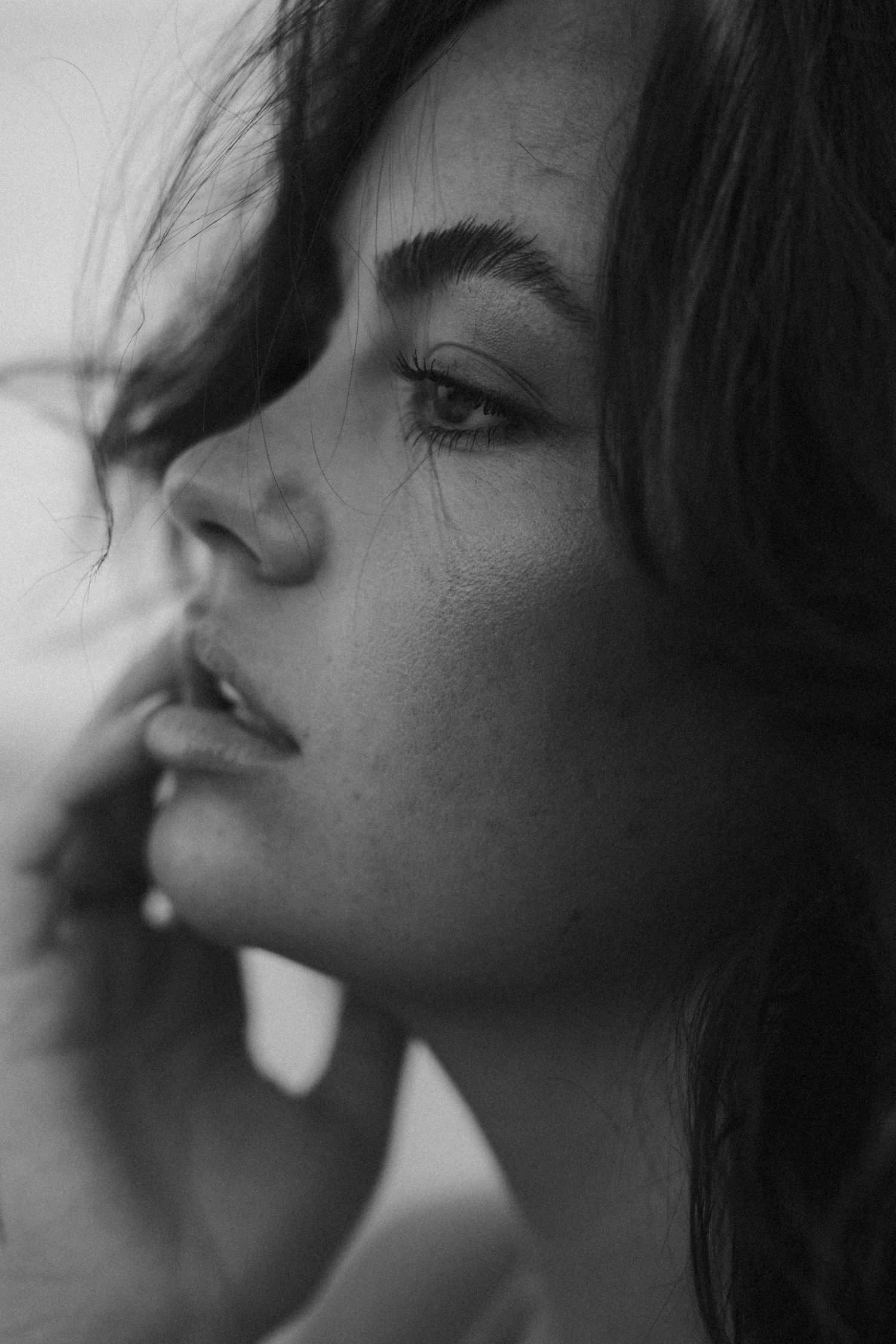 Moody black and white close-up portrait with dramatic side lighting.