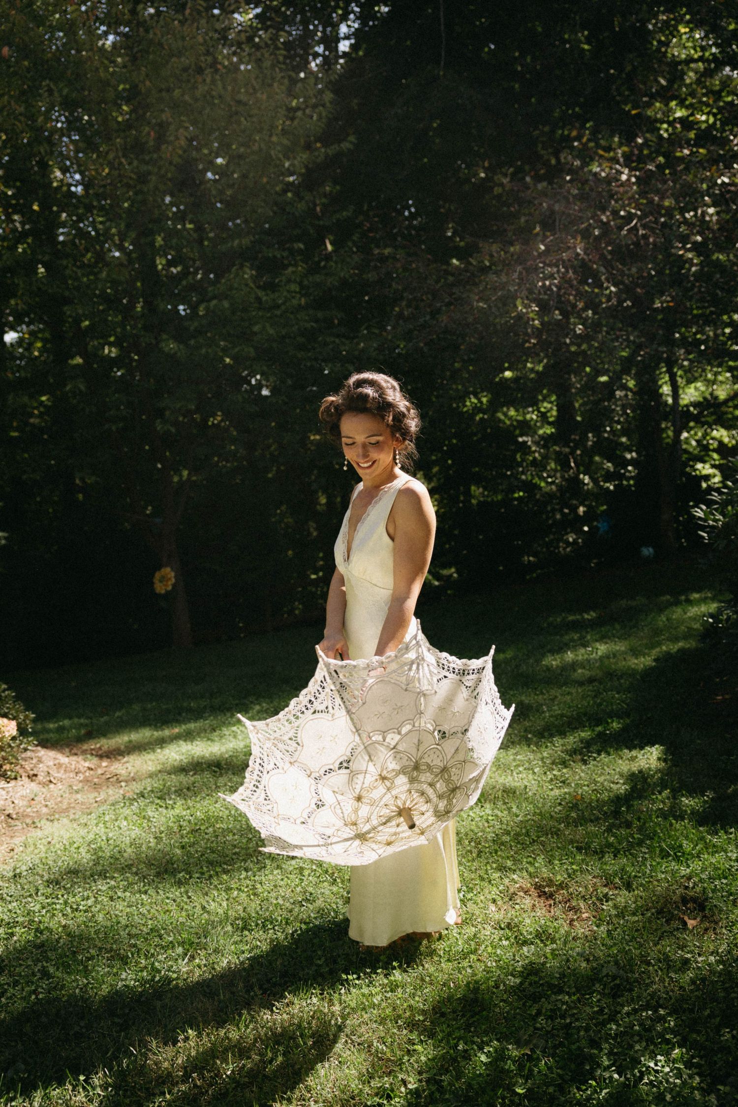 A figure in a flowing white dress twirls gracefully in a sunlit garden setting creating a dreamy outdoor scene.
