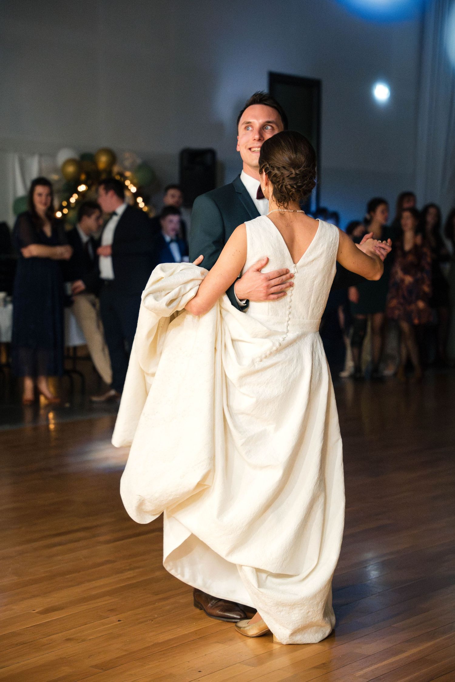 Un couple partage sa première danse lors d'une réception de mariage, la mariée portant une élégante robe blanche.
