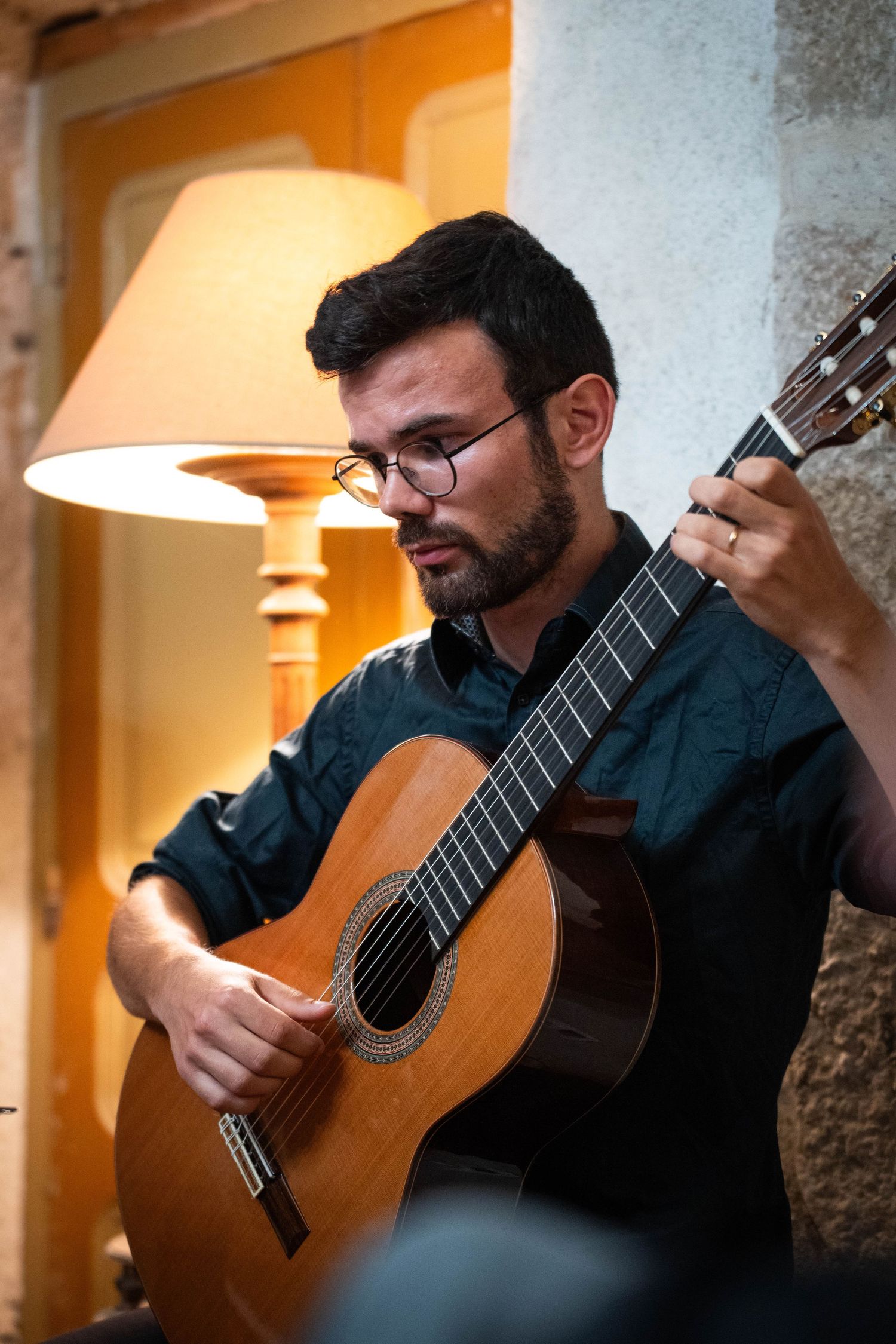 Un musicien joue de la guitare classique sous un éclairage chaleureux.
