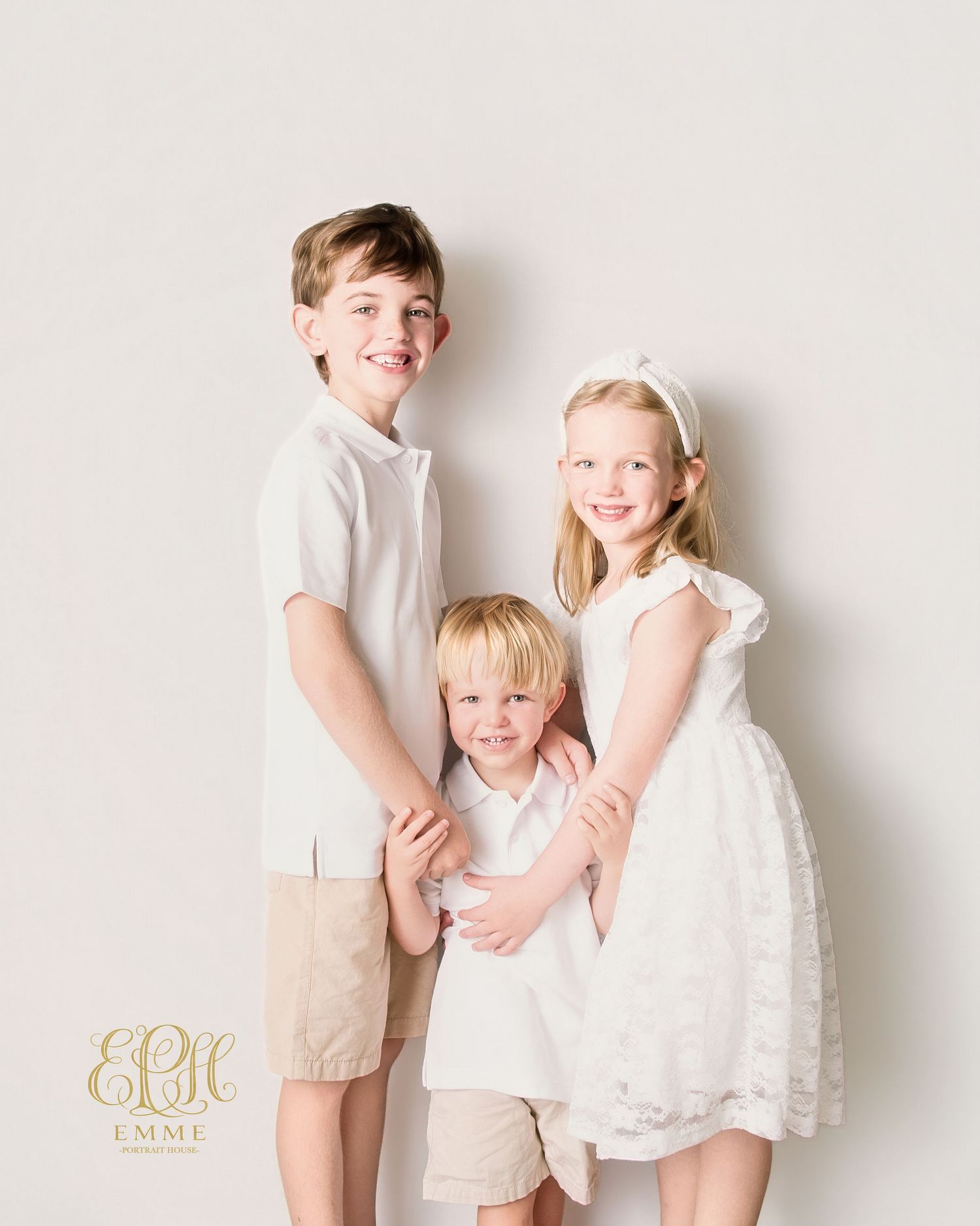 Three children in white and khaki outfits pose together for a professional portrait photo in Orangeburg, SC