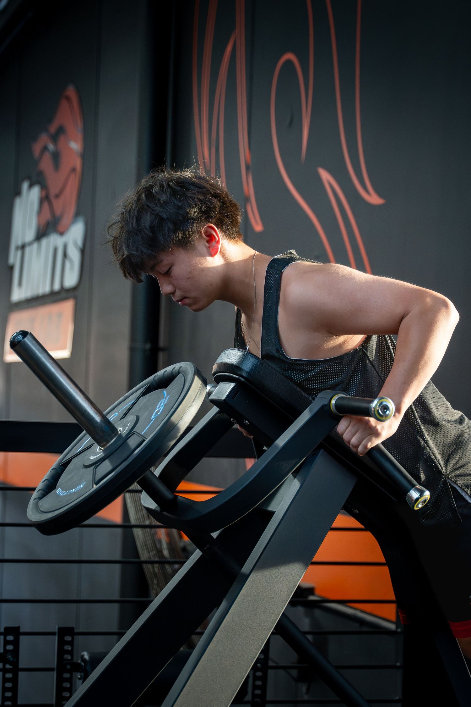 Person exercising on a weight bench in a dark gym with orange accents.