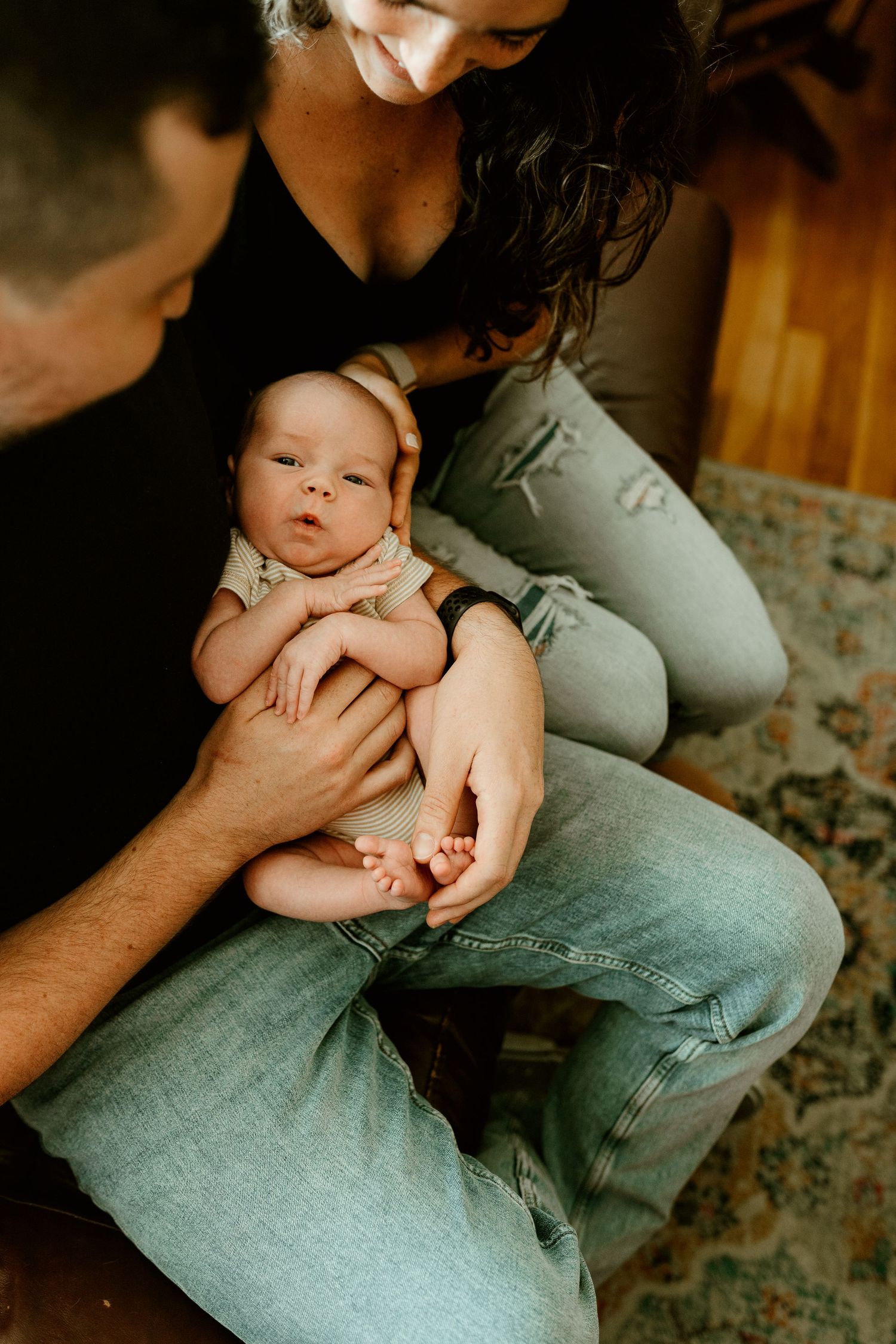 warm loving couple holding their newborn baby and looking happily down on it from above