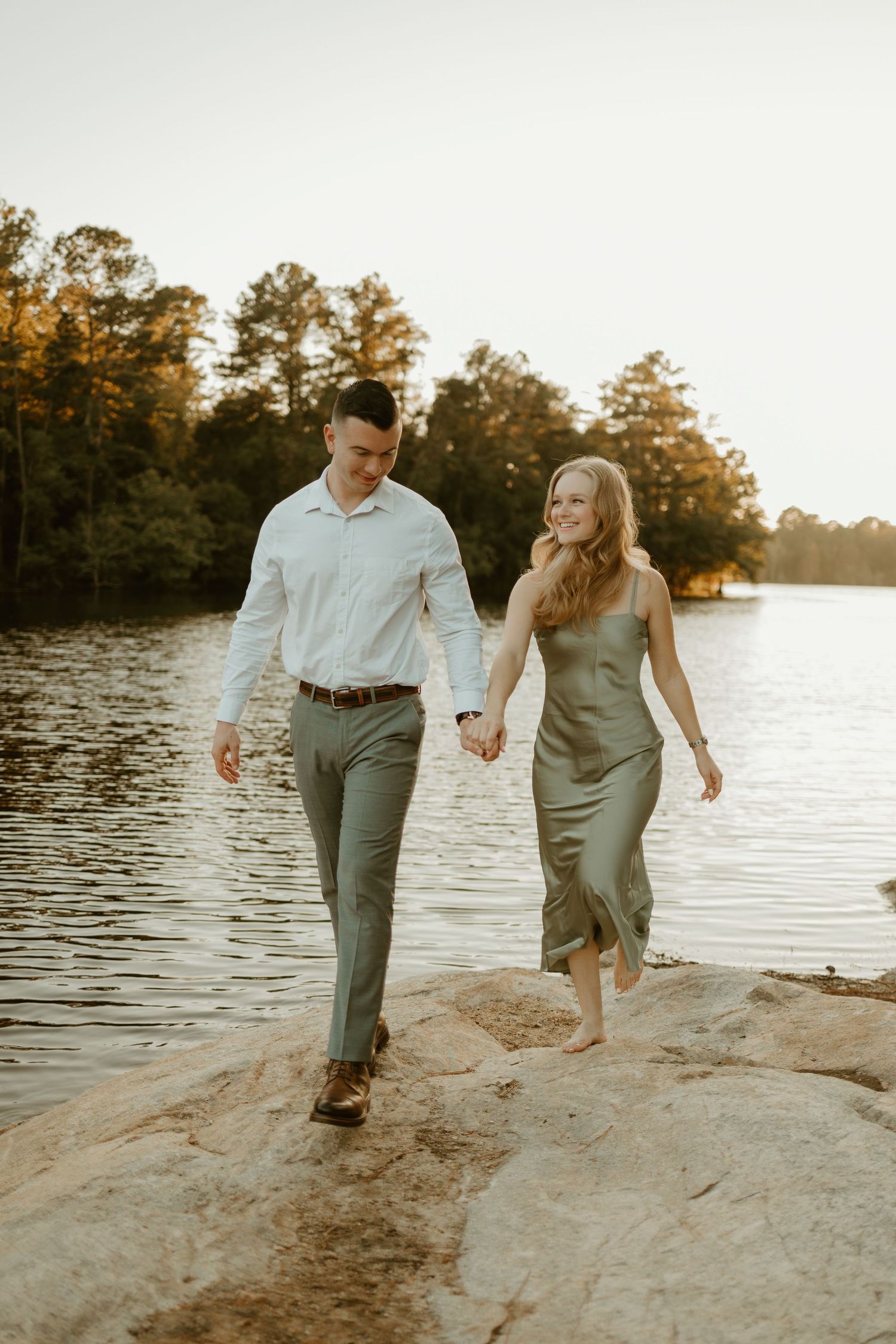 young couple stroll hand in hand by a quaint lake shore in north carolina at sunset