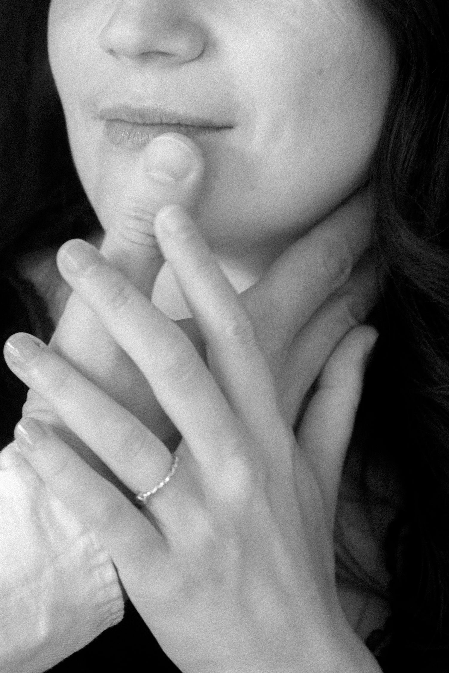 Black and white close-up photos showing a contemplative gesture with fingers touching lips while wearing a ring.