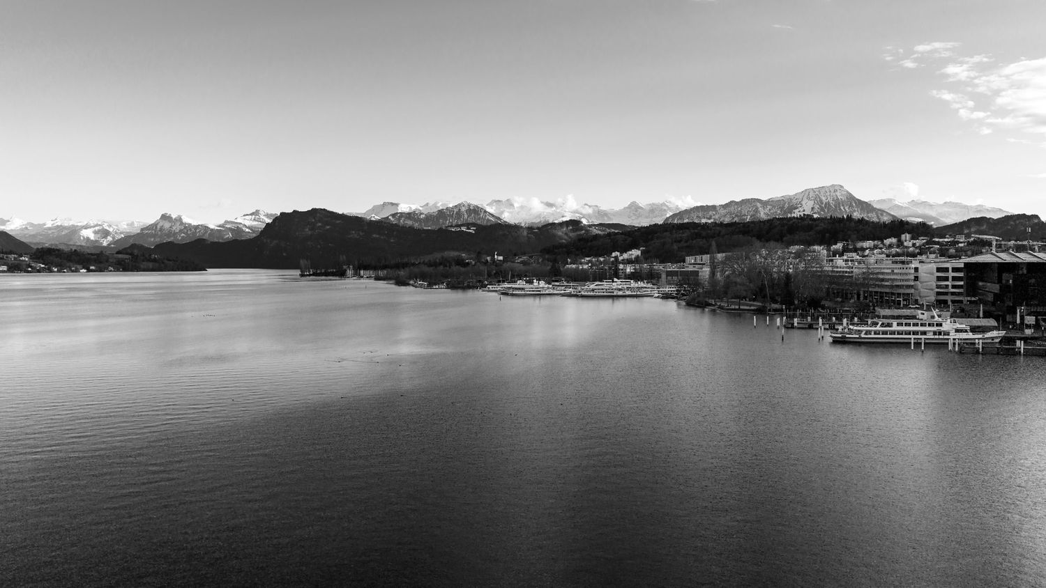 A black and white panoramic landscape view shows mountains, water, and a shoreline in dramatic monochrome tones.