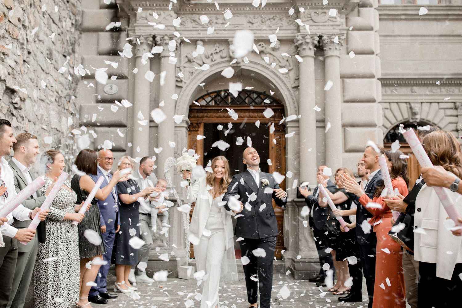 Wedding party celebration with white confetti flying outside a historic building. Rathaus Luzern