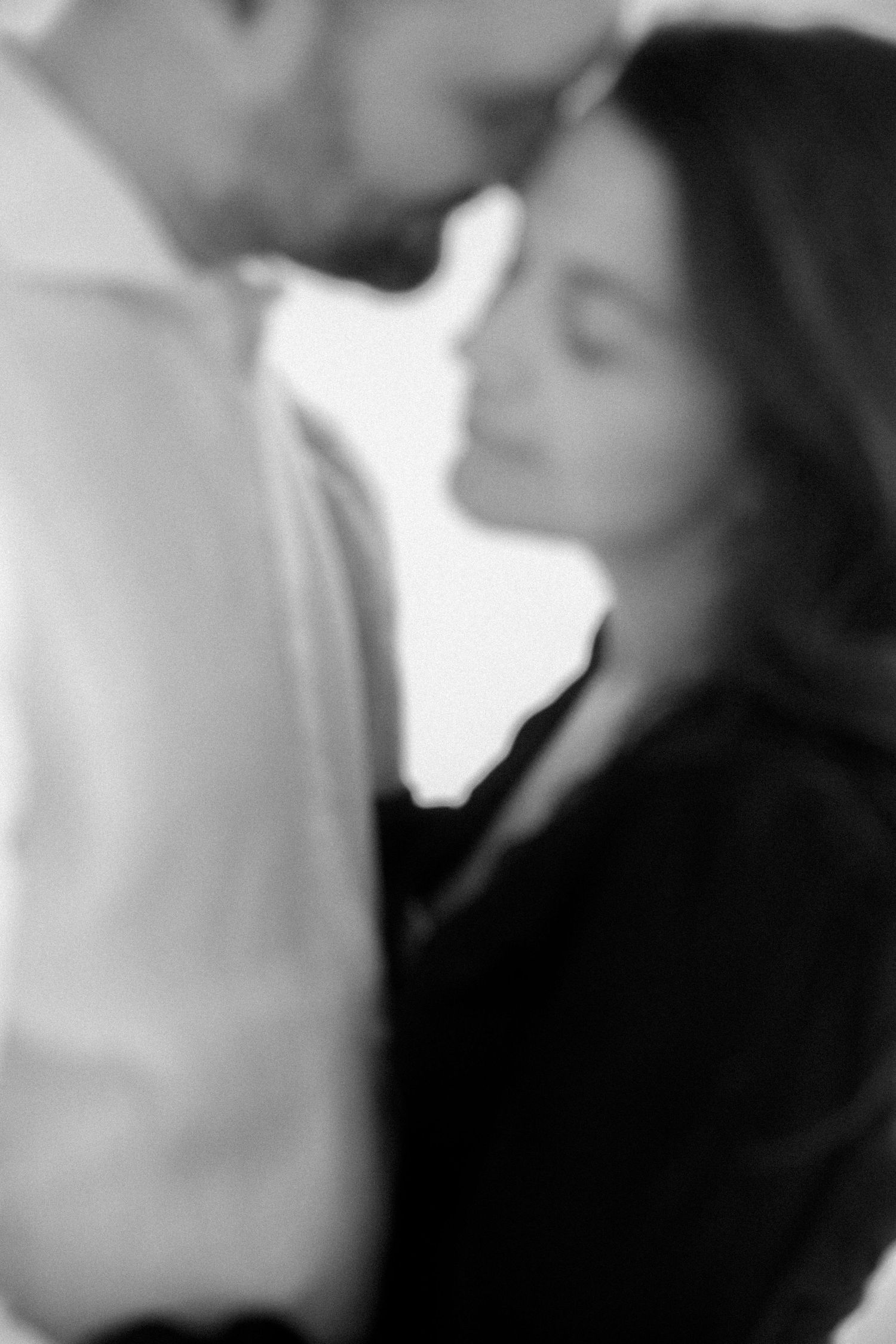 A soft black and white romantic portrait of a couple in an intimate moment.
