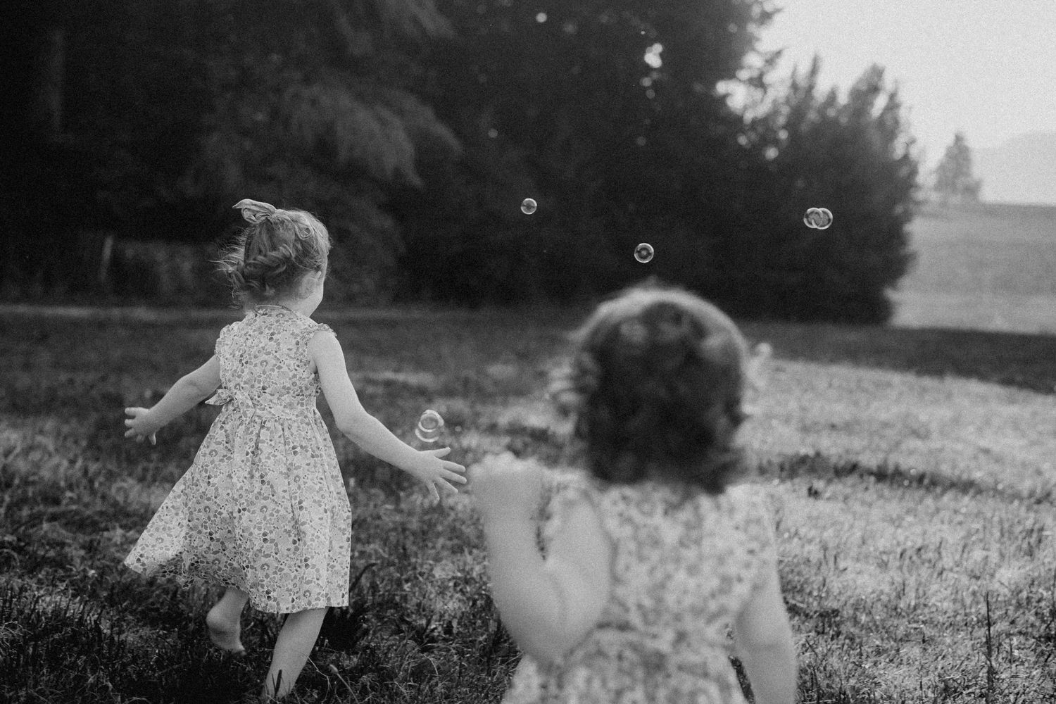 Black and white photos of children playing in a wildflower field during summer.