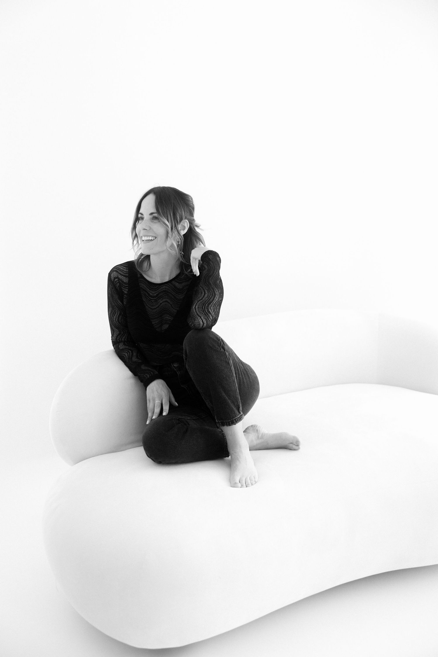 A black and white artistic portrait series showing a figure in dark clothing reclining on a white curved surface.