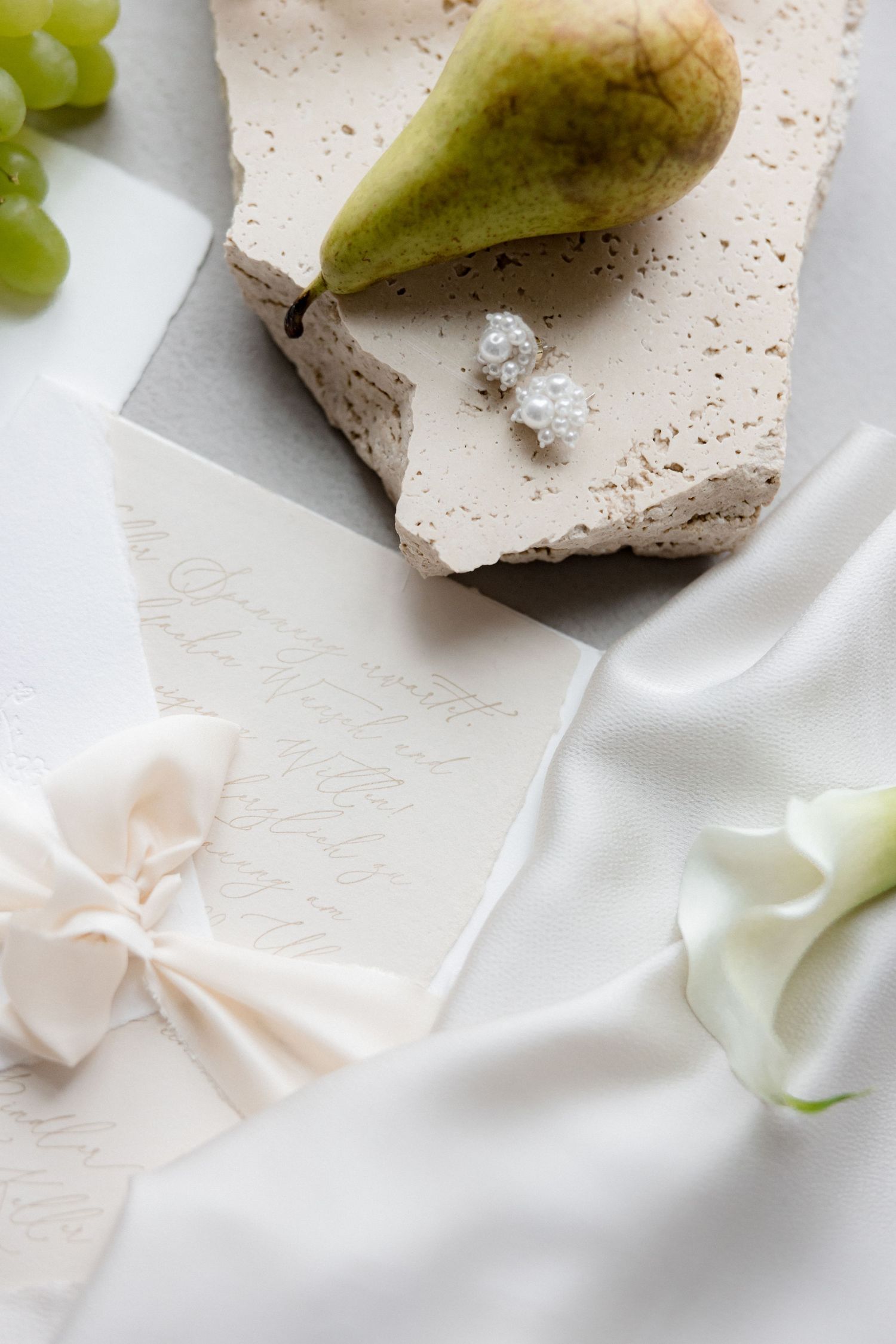 Fresh pears and grapes arranged on white textured surface with fabric. Flatlay Wedding Details