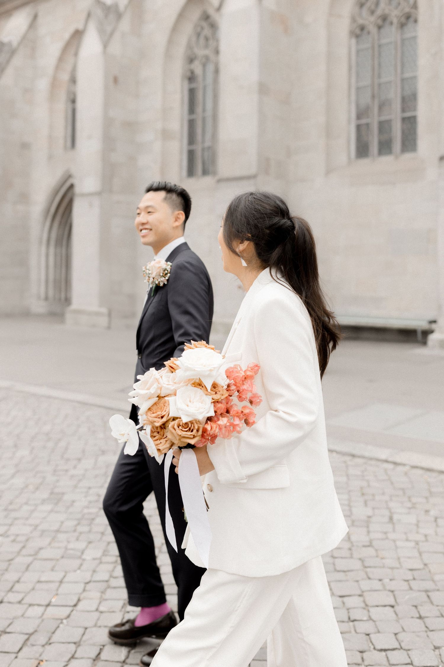 Couple sharing a joyful moment on cobblestone streets in front of a historic building.