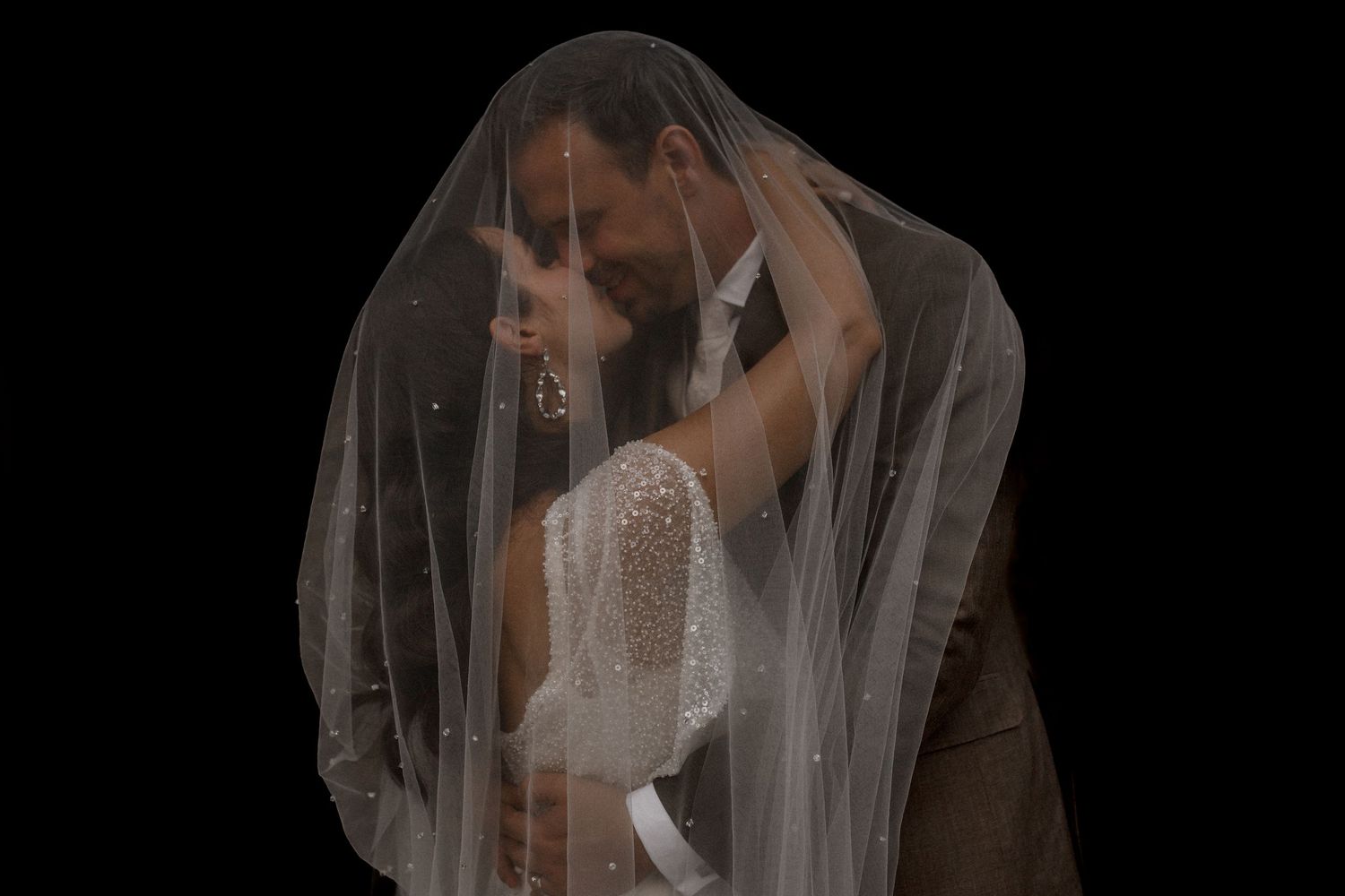 Artistic wedding portrait through sheer veil creating a romantic silhouette against dark background at Villa Sassa Lugano.