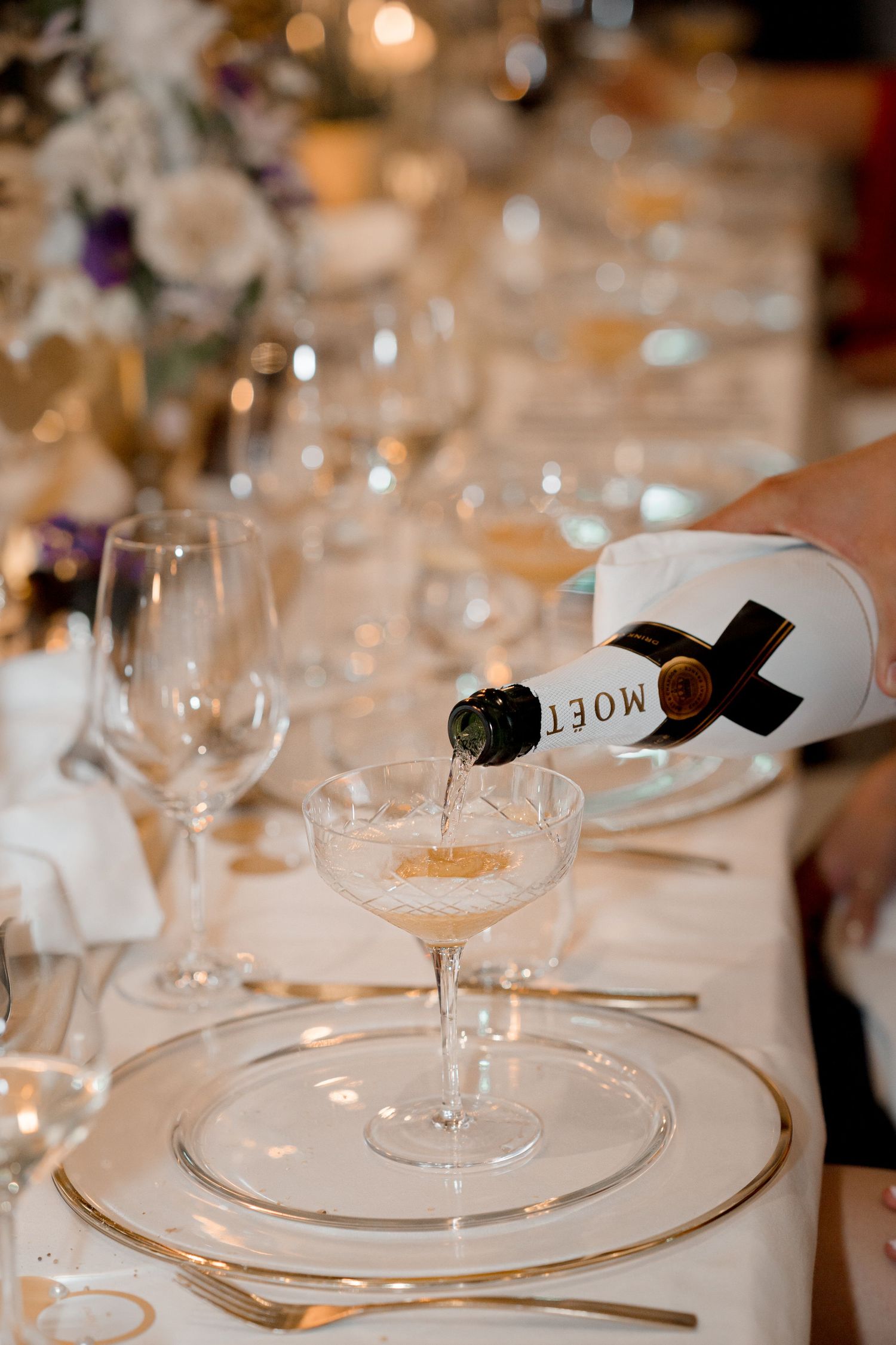 Champagne being poured into a coupe glass at an elegant wedding reception table setting at Bürgenstock Resort