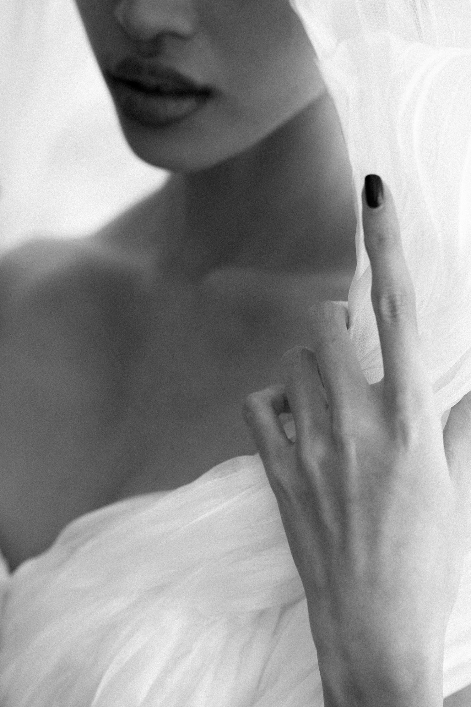 Black and white portrait of a woman in white dress with dark nail polish, elegant and artistic photography.