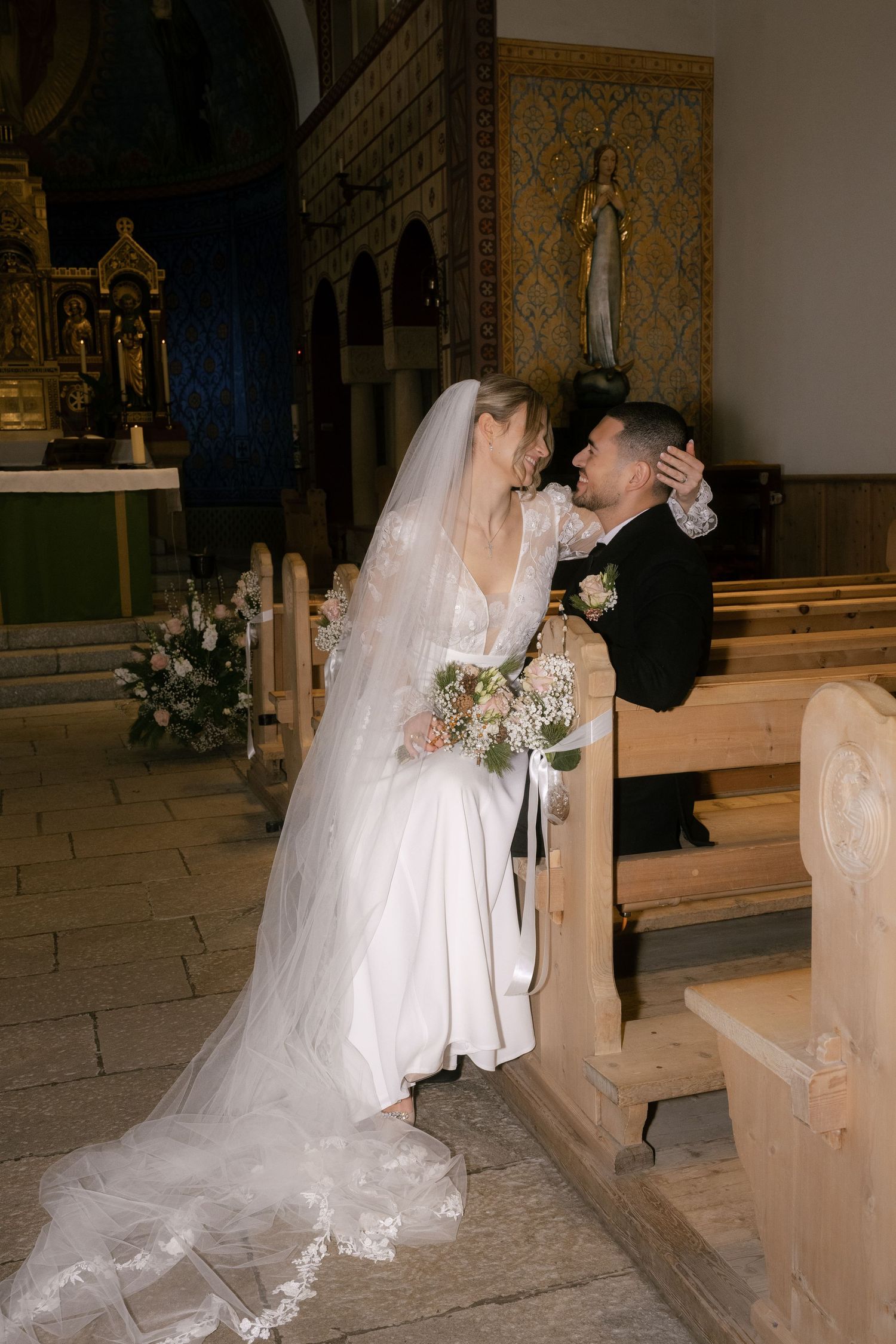 Bride and groom share a romantic kiss at the altar inside a beautiful church on their wedding day.
