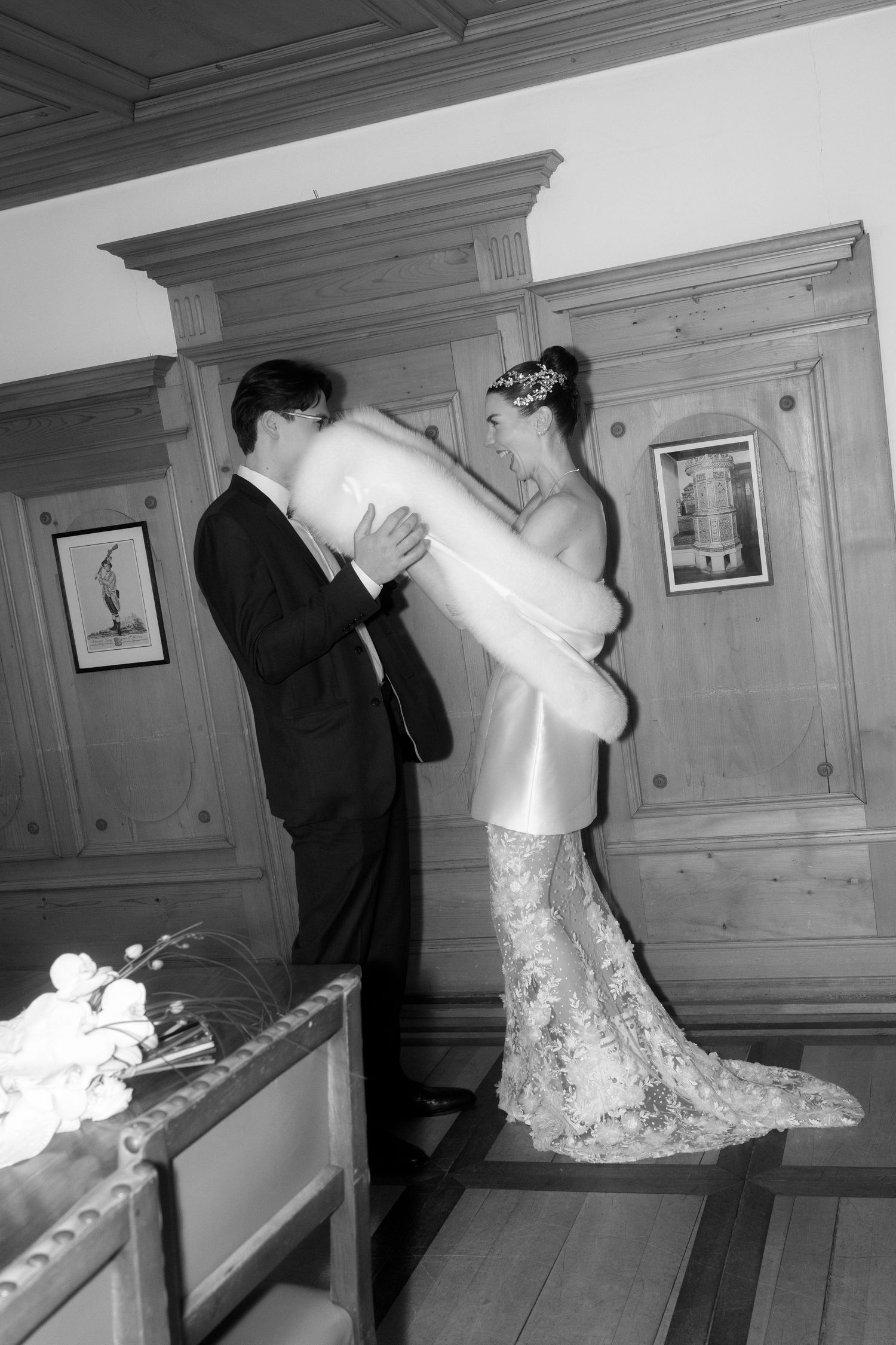 A sequence of black and white photos showing a playful pillow fight between two people in formal attire.