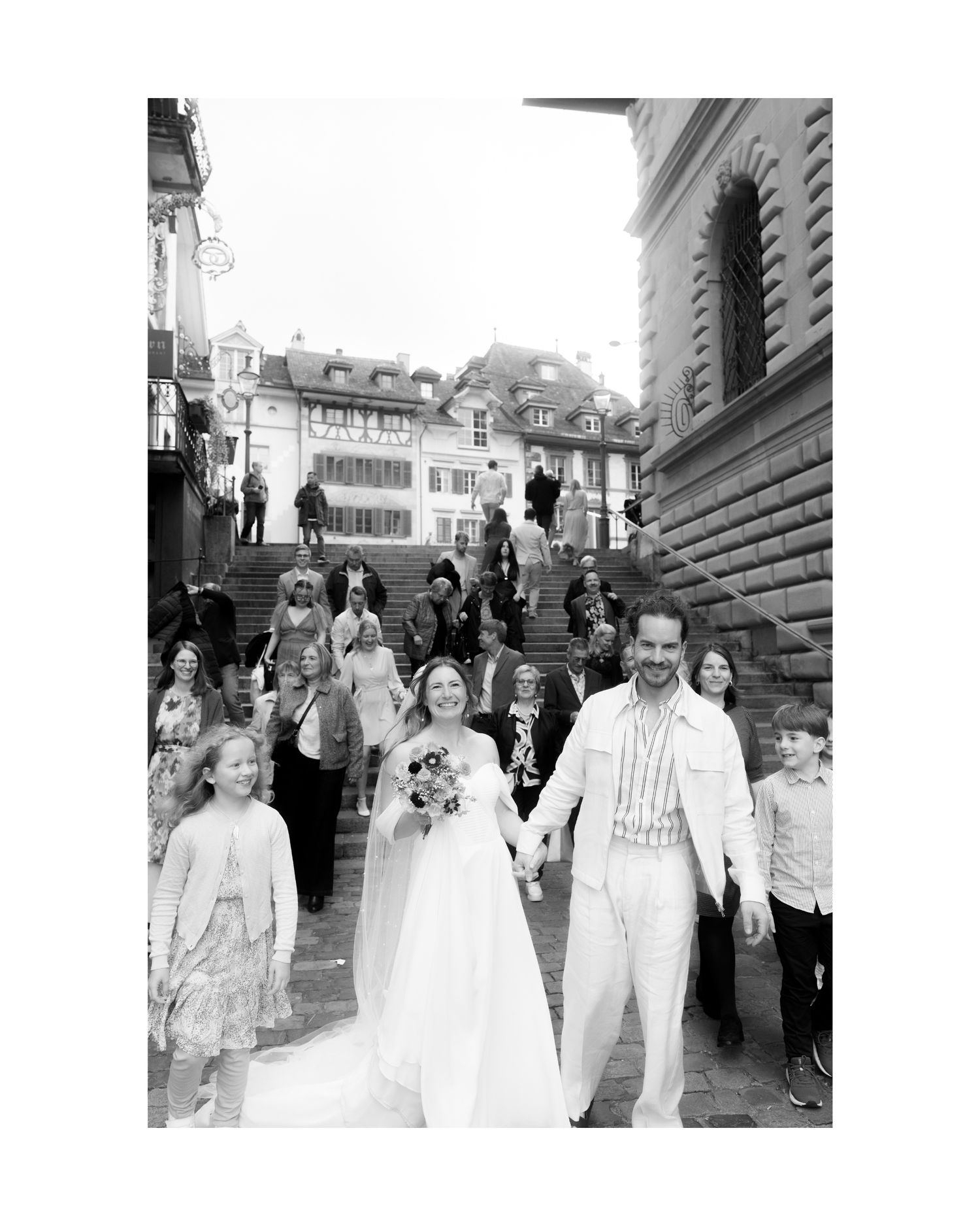 A group of people in formal attire walk together outdoors in a black and white vintage photograph.