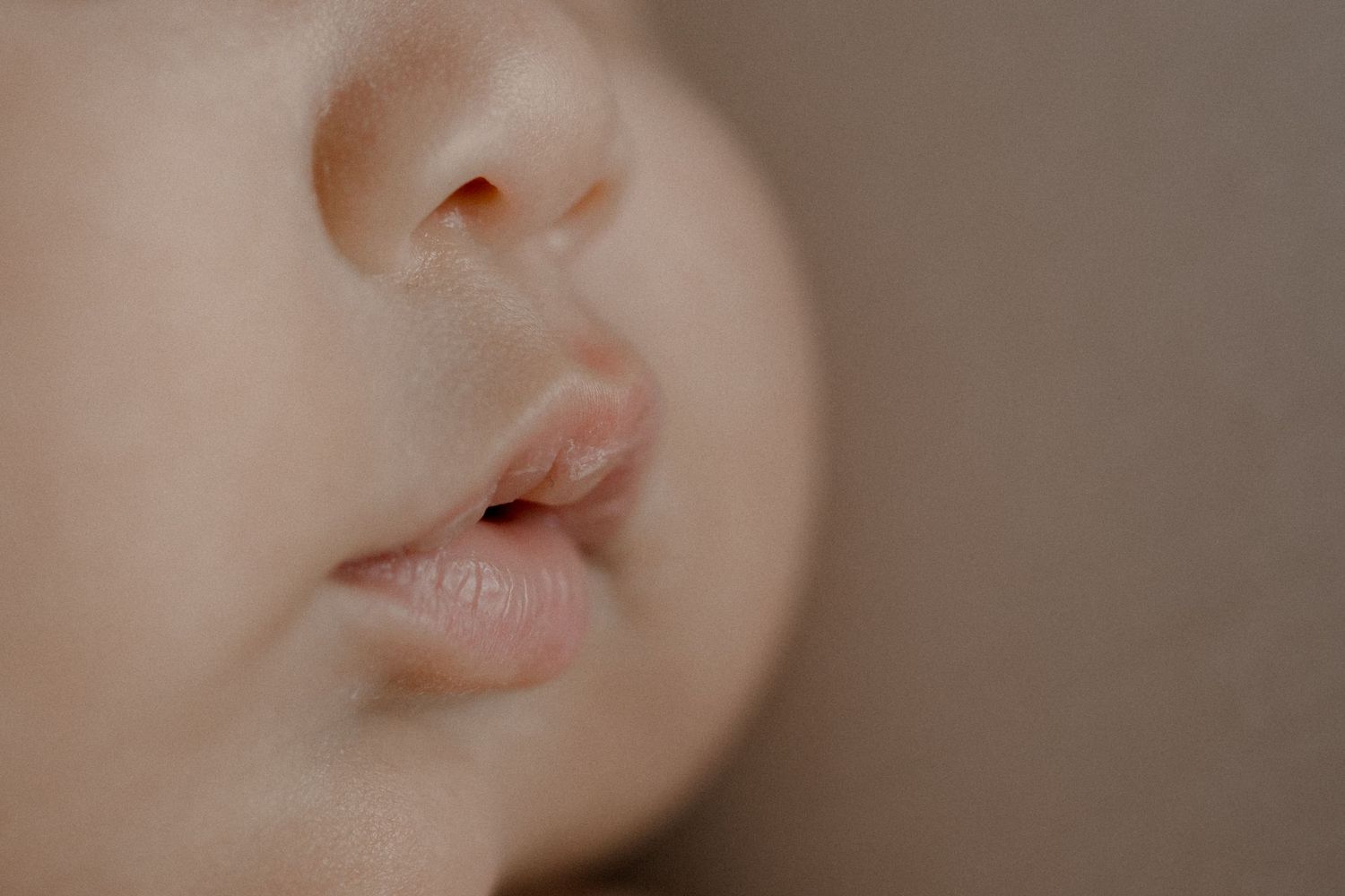 Extreme close-up macro photo of lips and skin in soft, neutral tones.