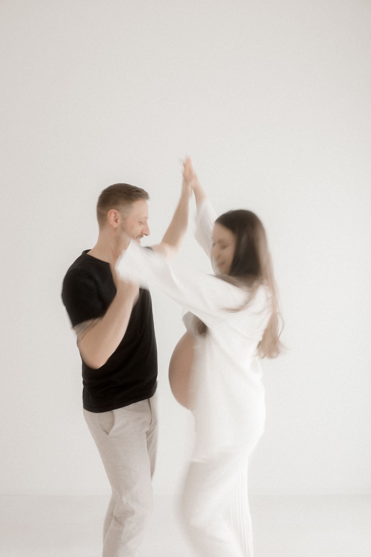 Dynamic motion shots of couple dancing in white studio setting.