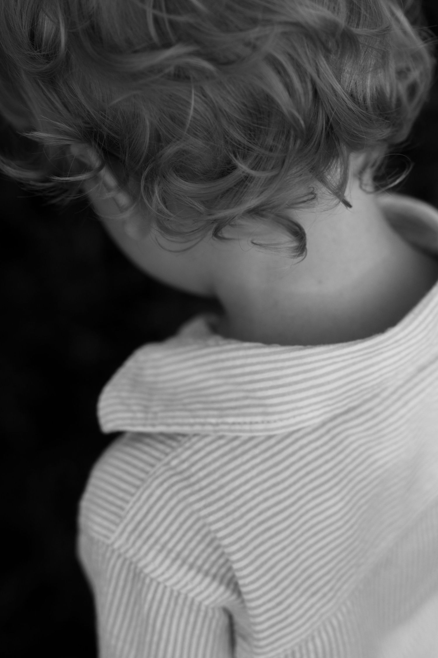 Close-up black and white detail of curly hair and striped clothing.