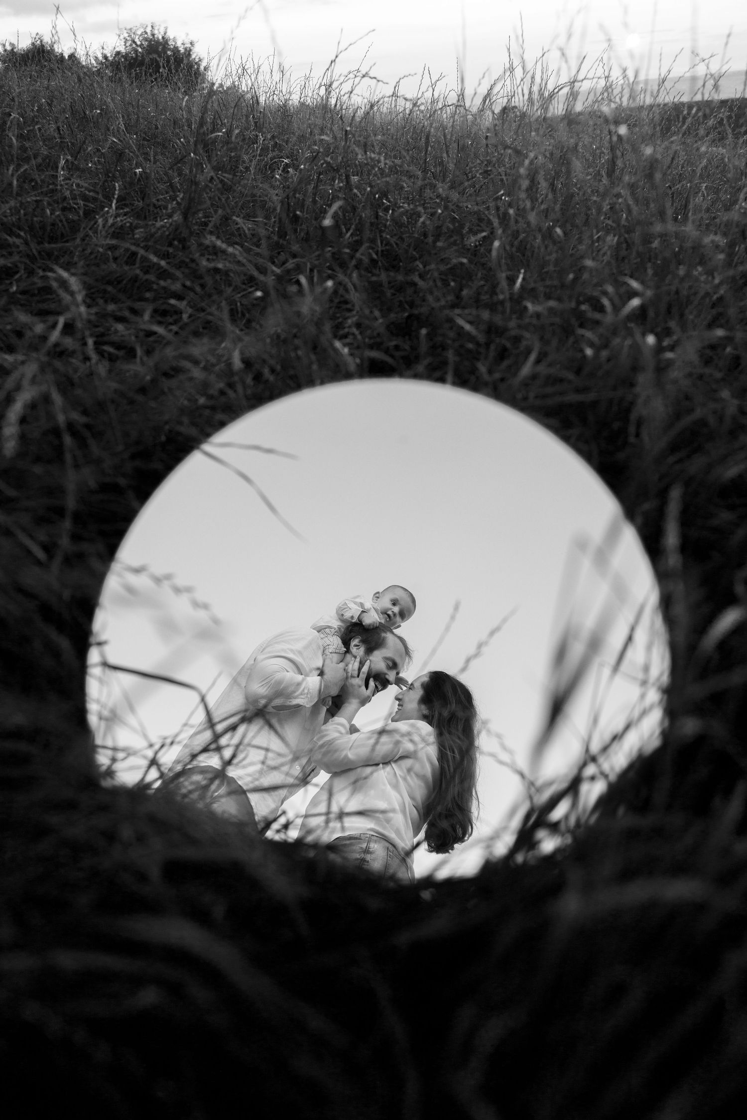 Artistic silhouette of family moment framed by tall grass.