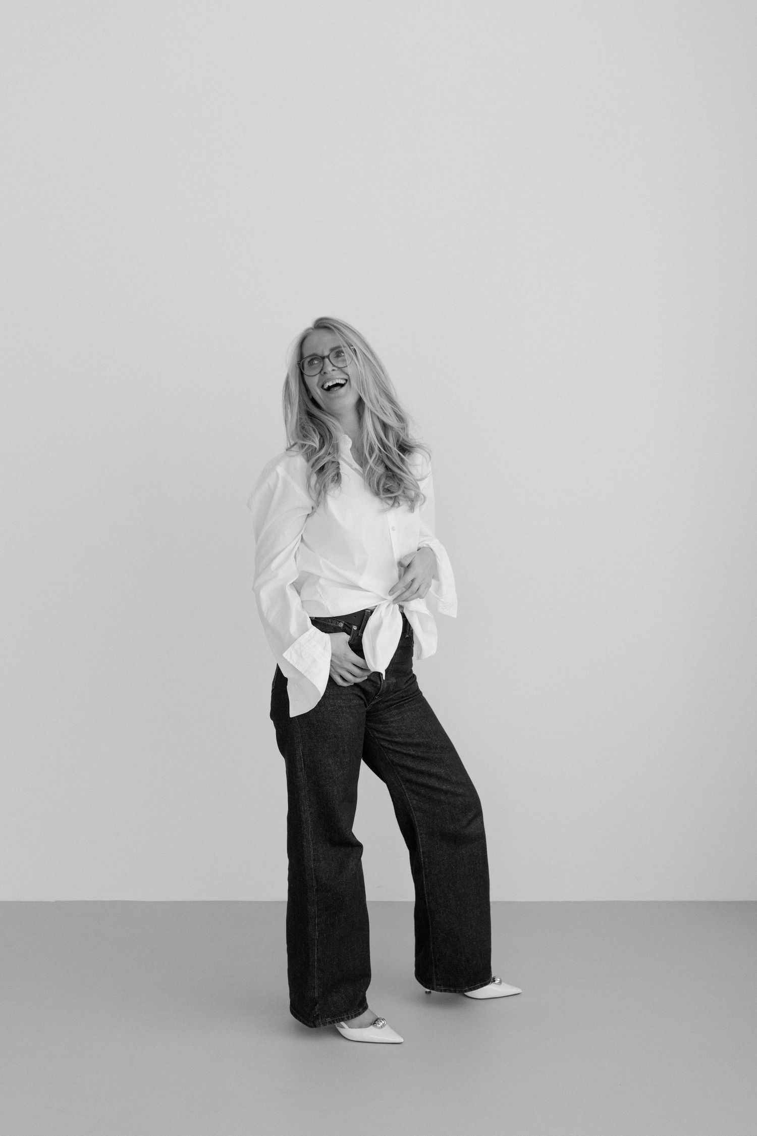 A series of black and white fashion photos showing a person in white top and black pants posing against a light background.