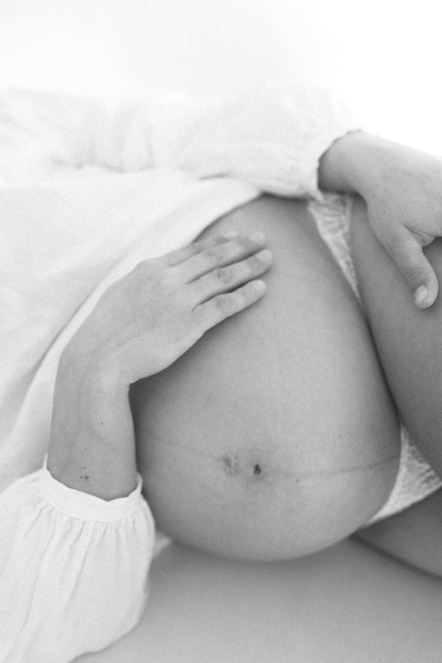 Close-up black and white photos showing the progression of a pregnant belly through different stages of pregnancy.