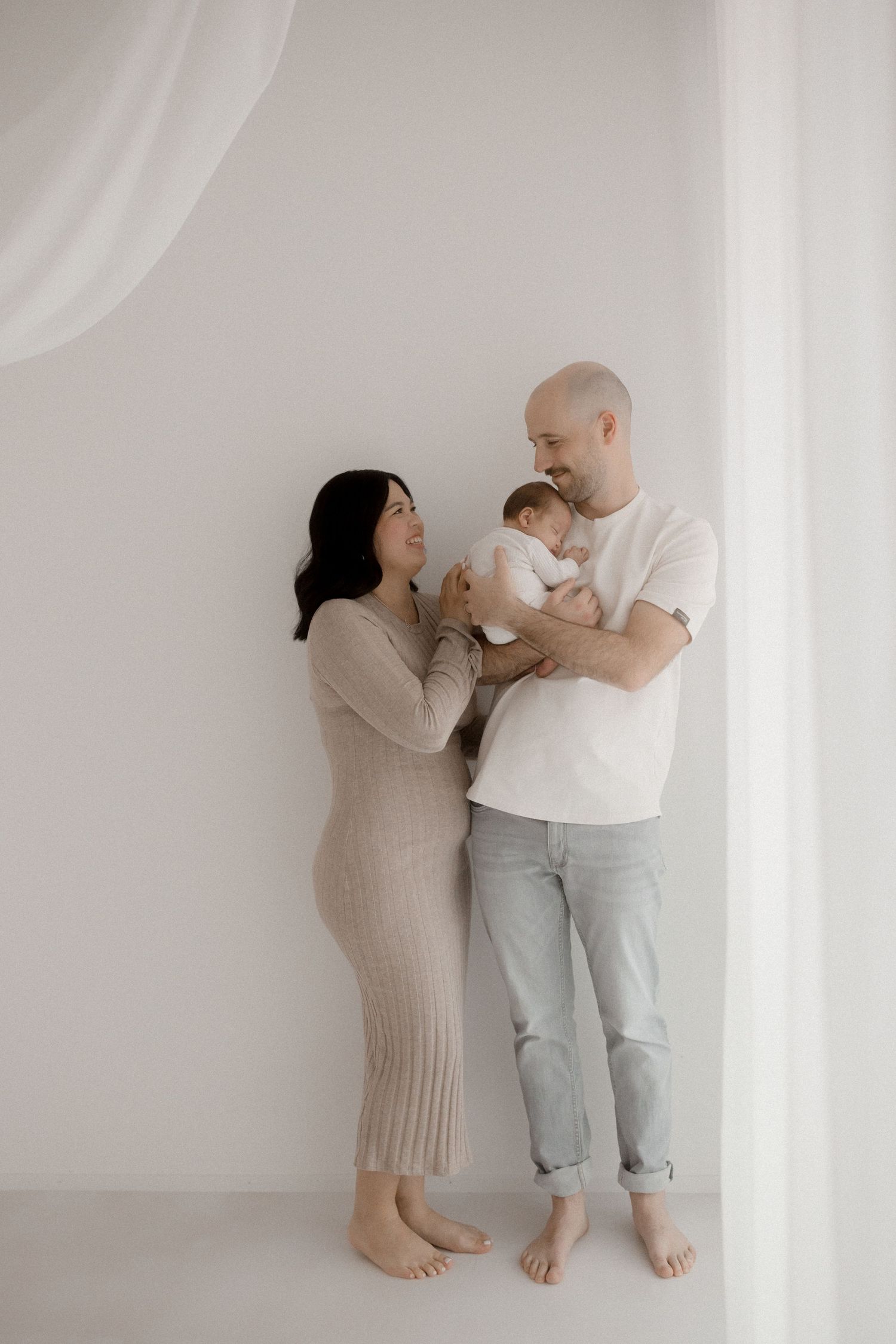 A tender family moment captured against a soft white backdrop in minimalist style.